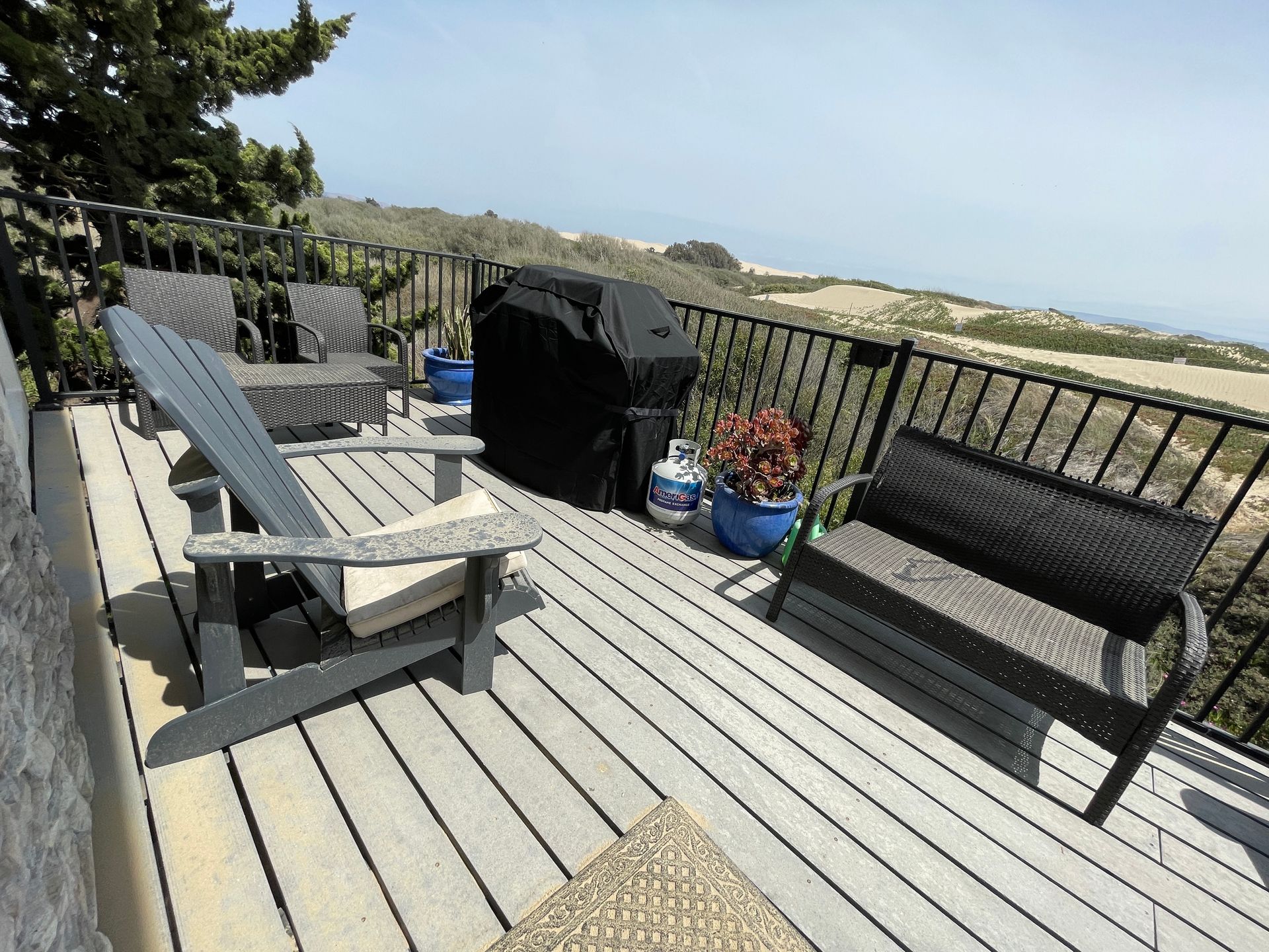 A deck with chairs and a grill with a view of the ocean