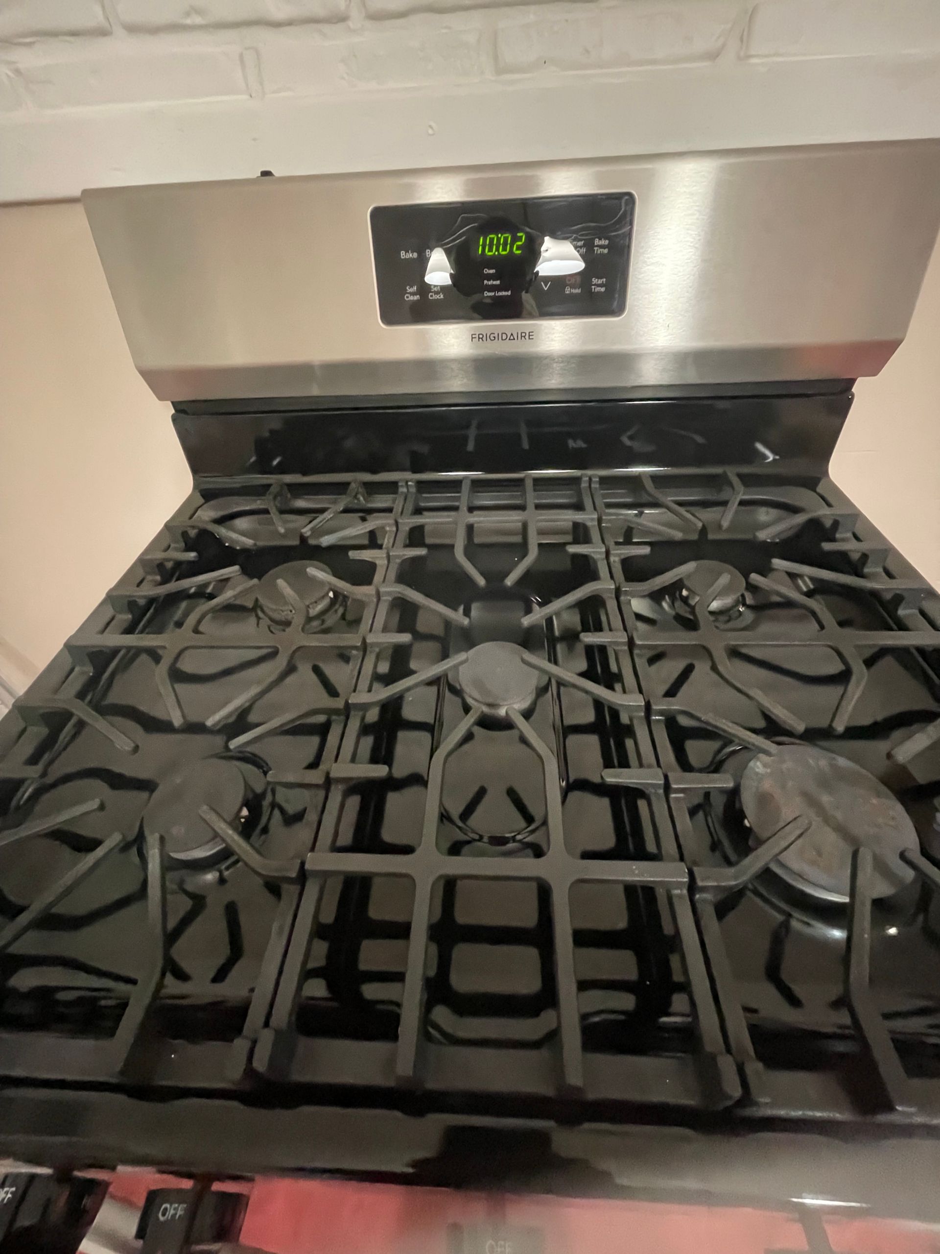 Black gas stove with stainless steel hood and digital display.