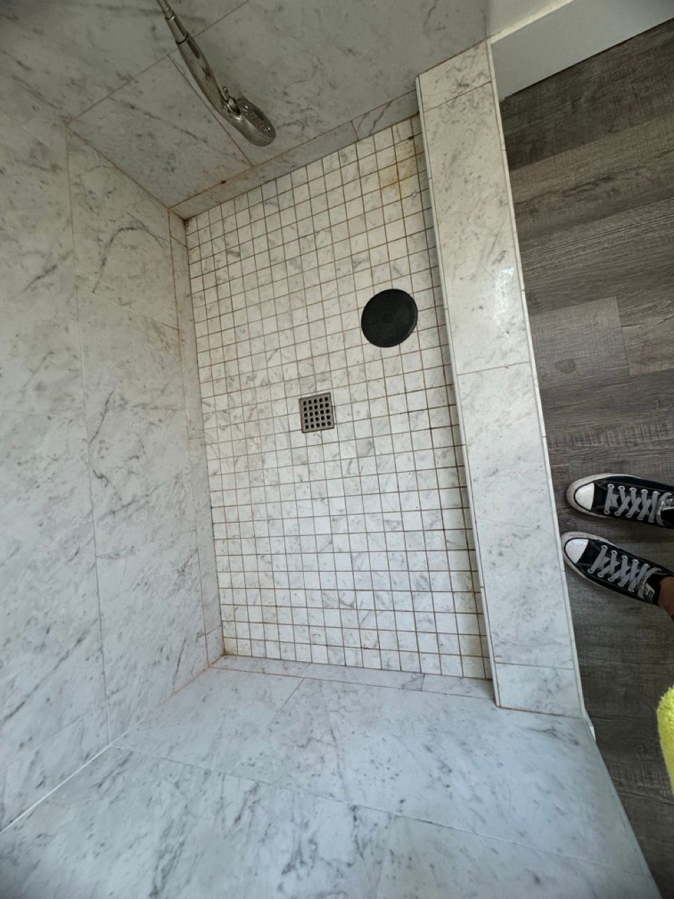 A person is standing in a bathroom with a walk in shower.