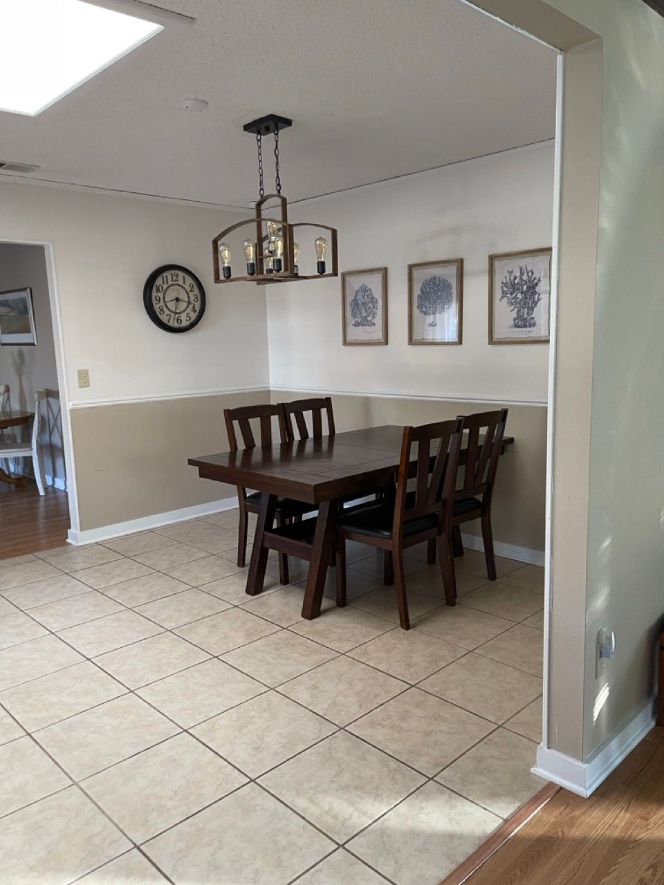 A dining room with a table and chairs and a clock on the wall