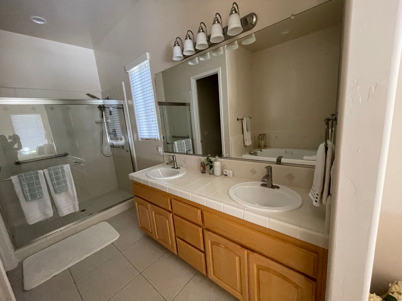 A bathroom with two sinks , a shower and a mirror.