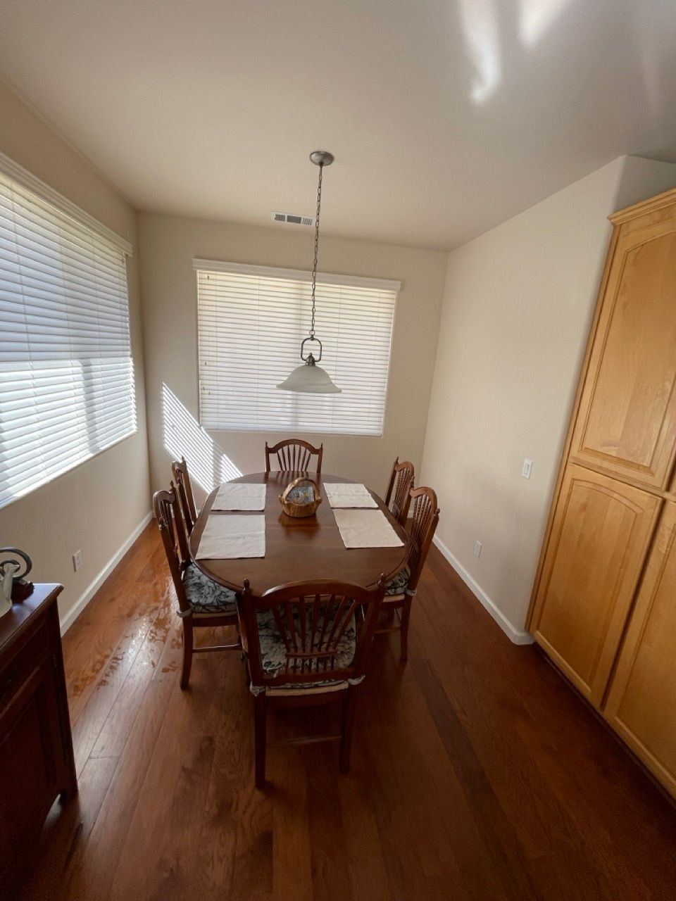 A dining room with a table and chairs and blinds on the windows