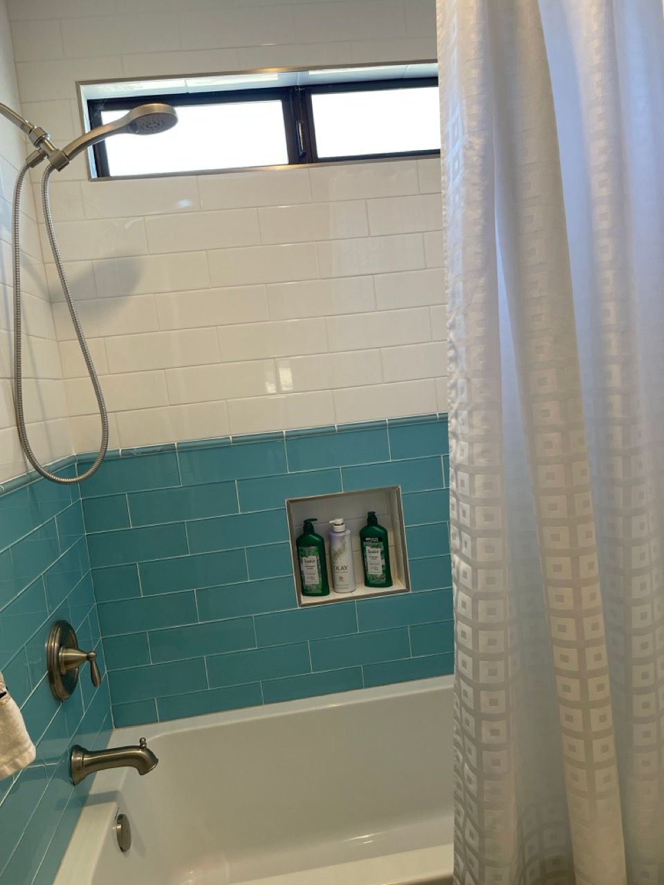 A bathroom with blue tiles and a white shower curtain