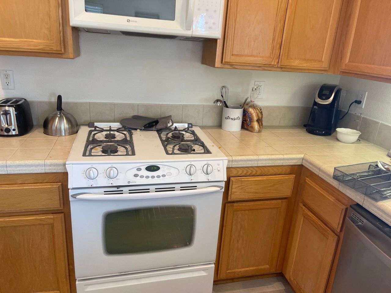 A kitchen with a stove , microwave , toaster and dishwasher