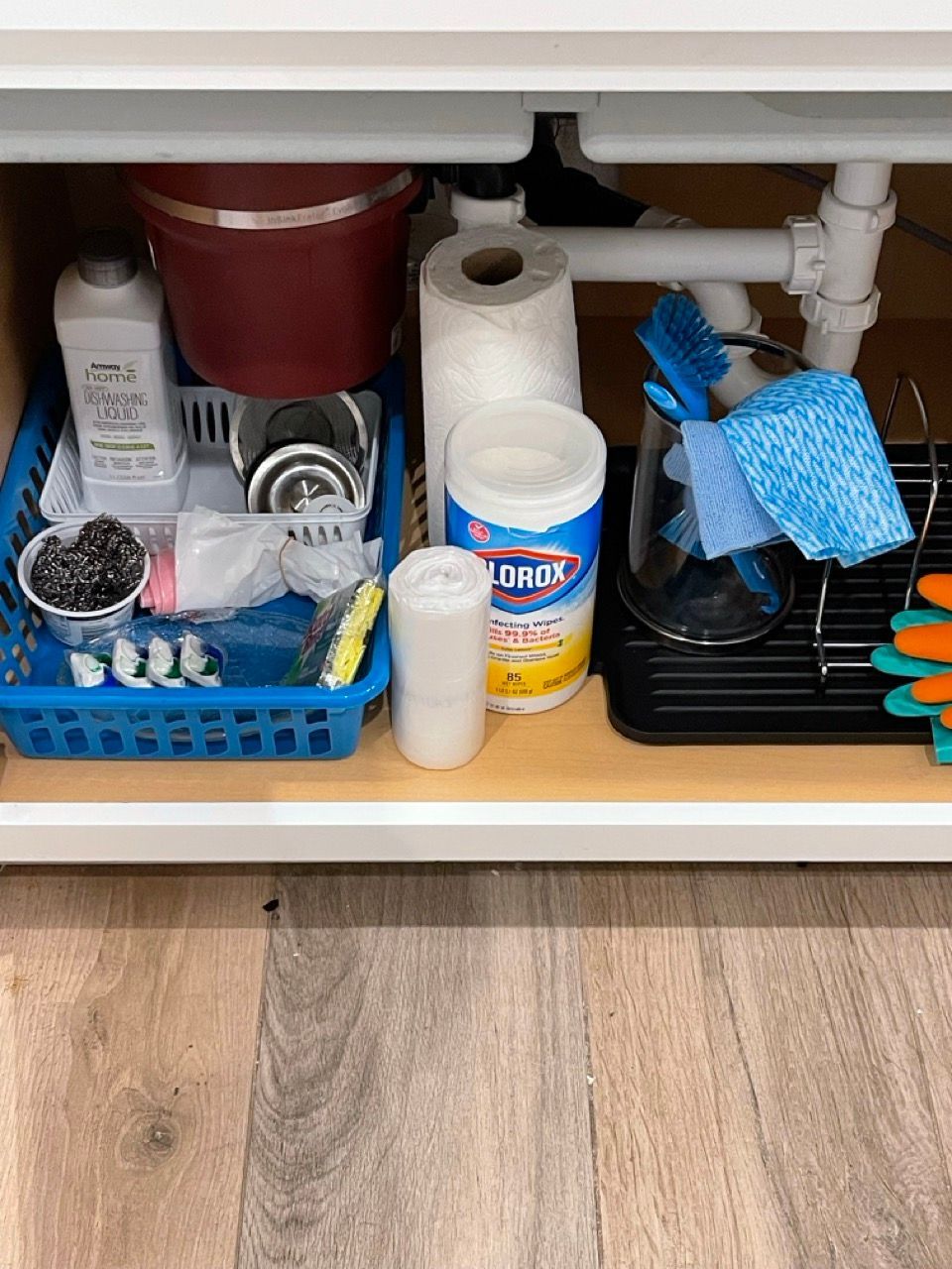 A kitchen sink filled with cleaning supplies including clorox wipes