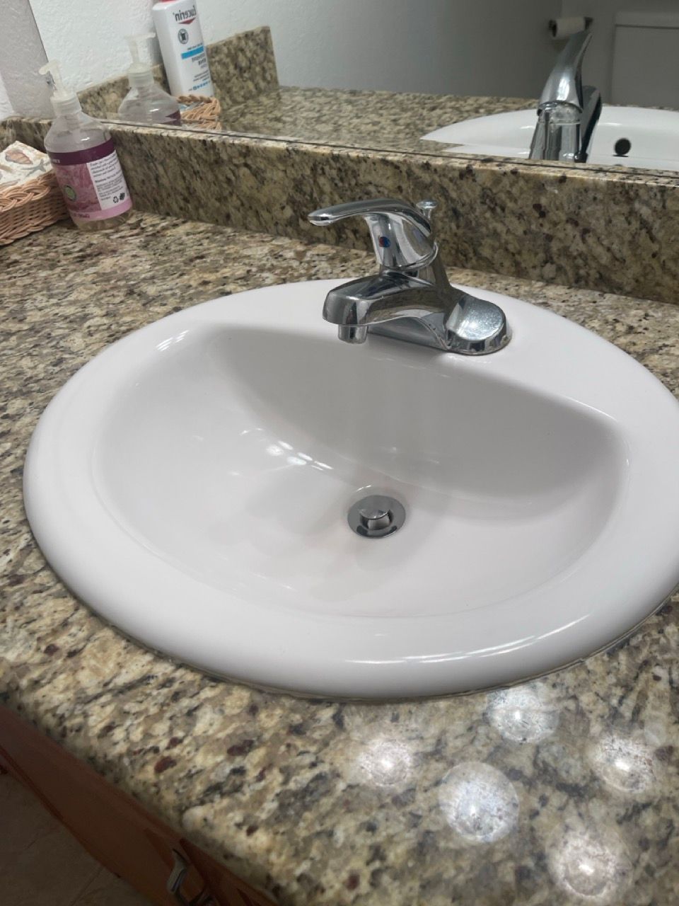 A bathroom sink with a faucet on a granite counter top.