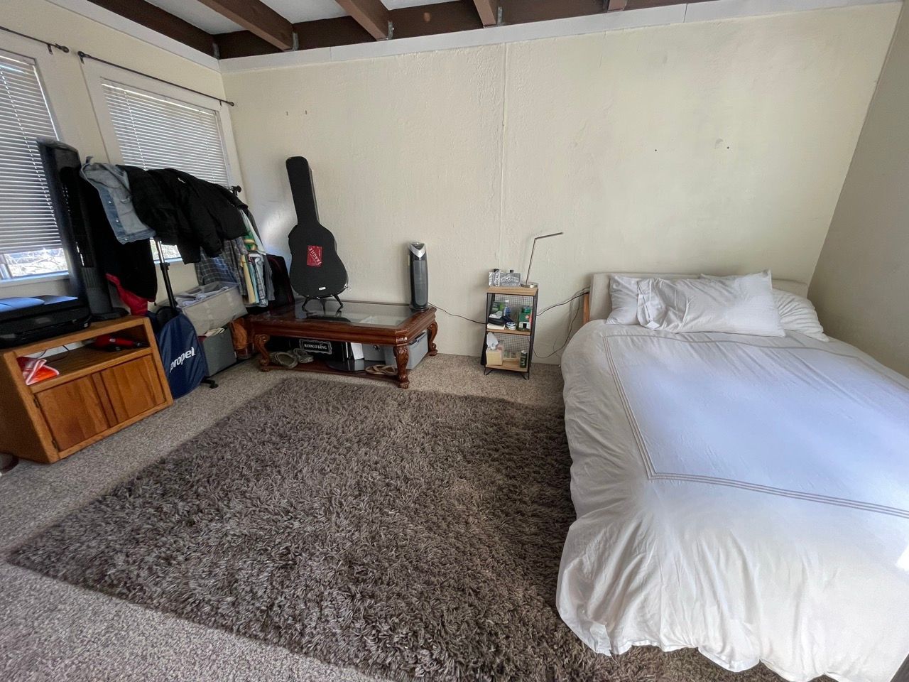 A bedroom with a bed and a guitar case on the wall