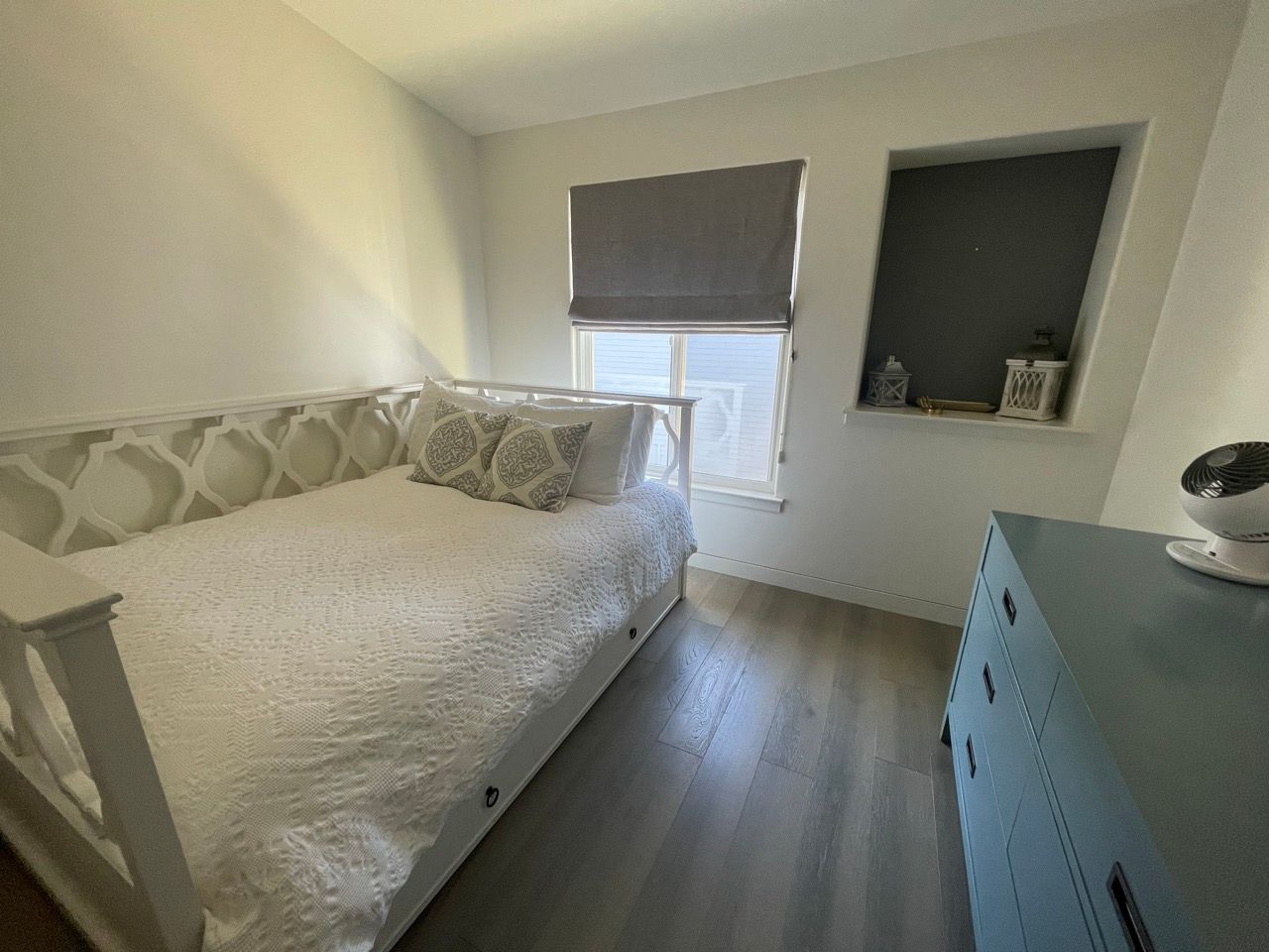 A bedroom with a day bed and a blue dresser.
