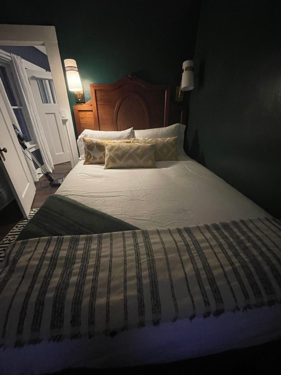 A bedroom with a bed and a lamp on the wall