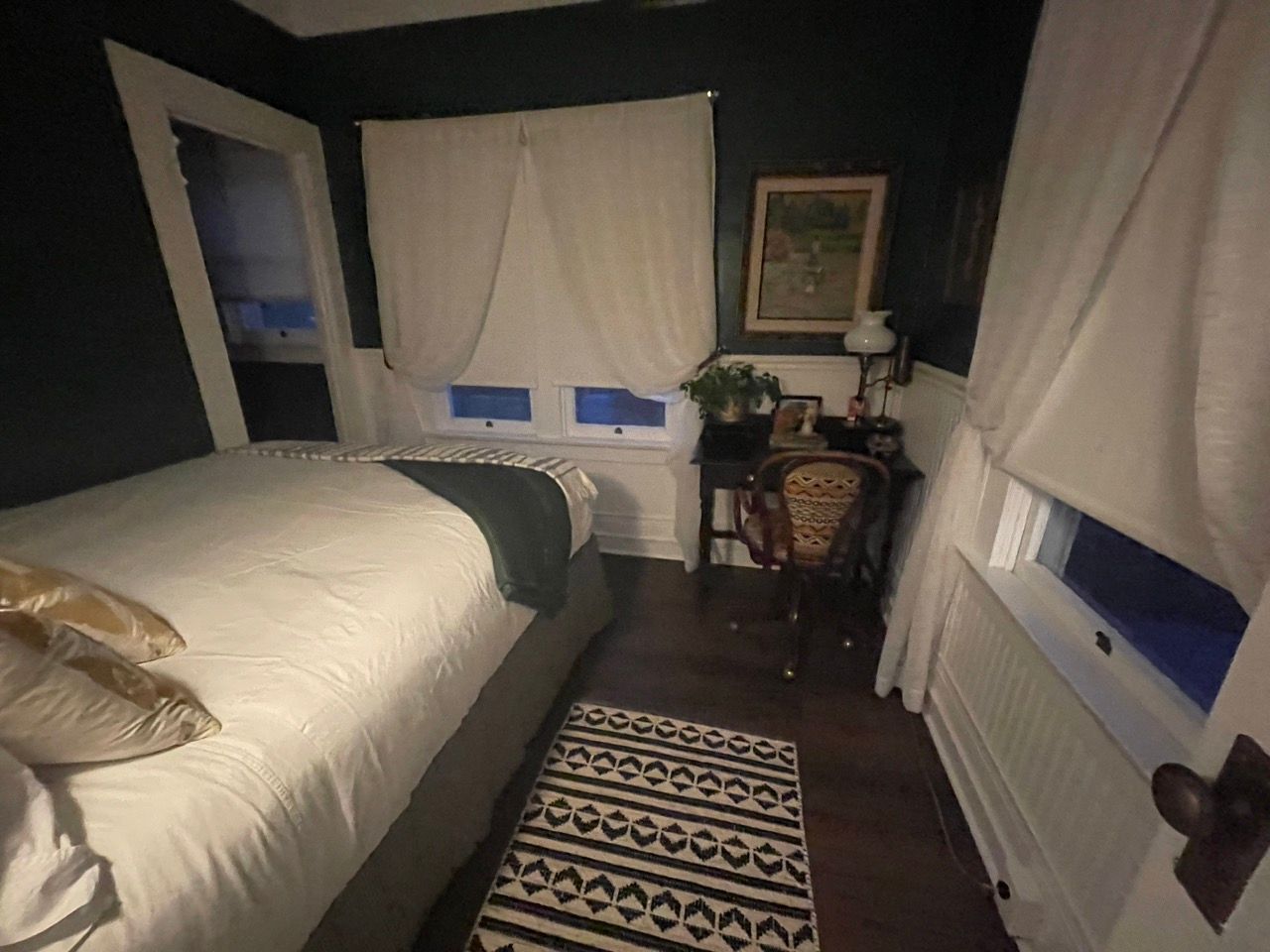 A bedroom with a bed a desk and a rug