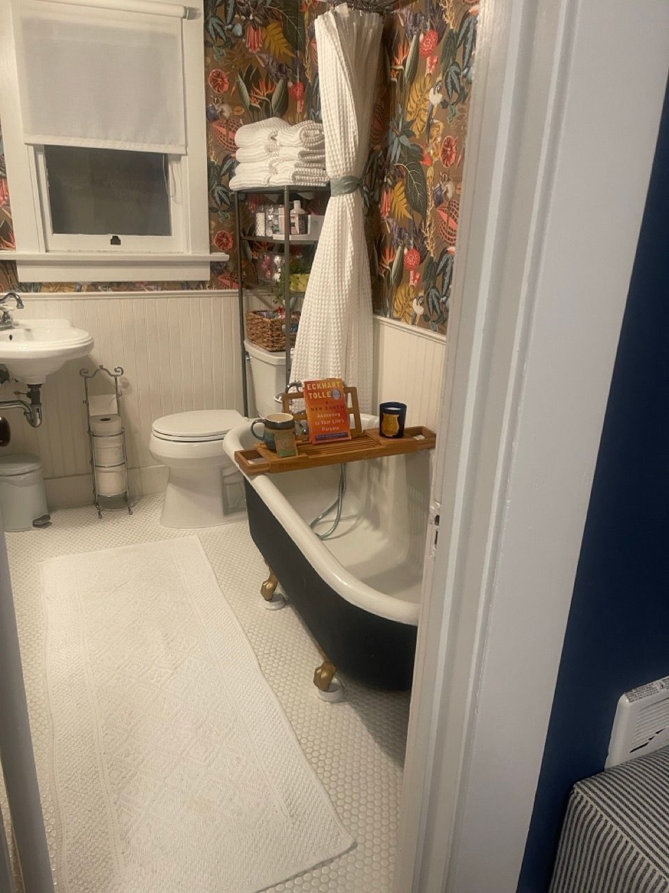 A bathroom with a tub , toilet , sink and window