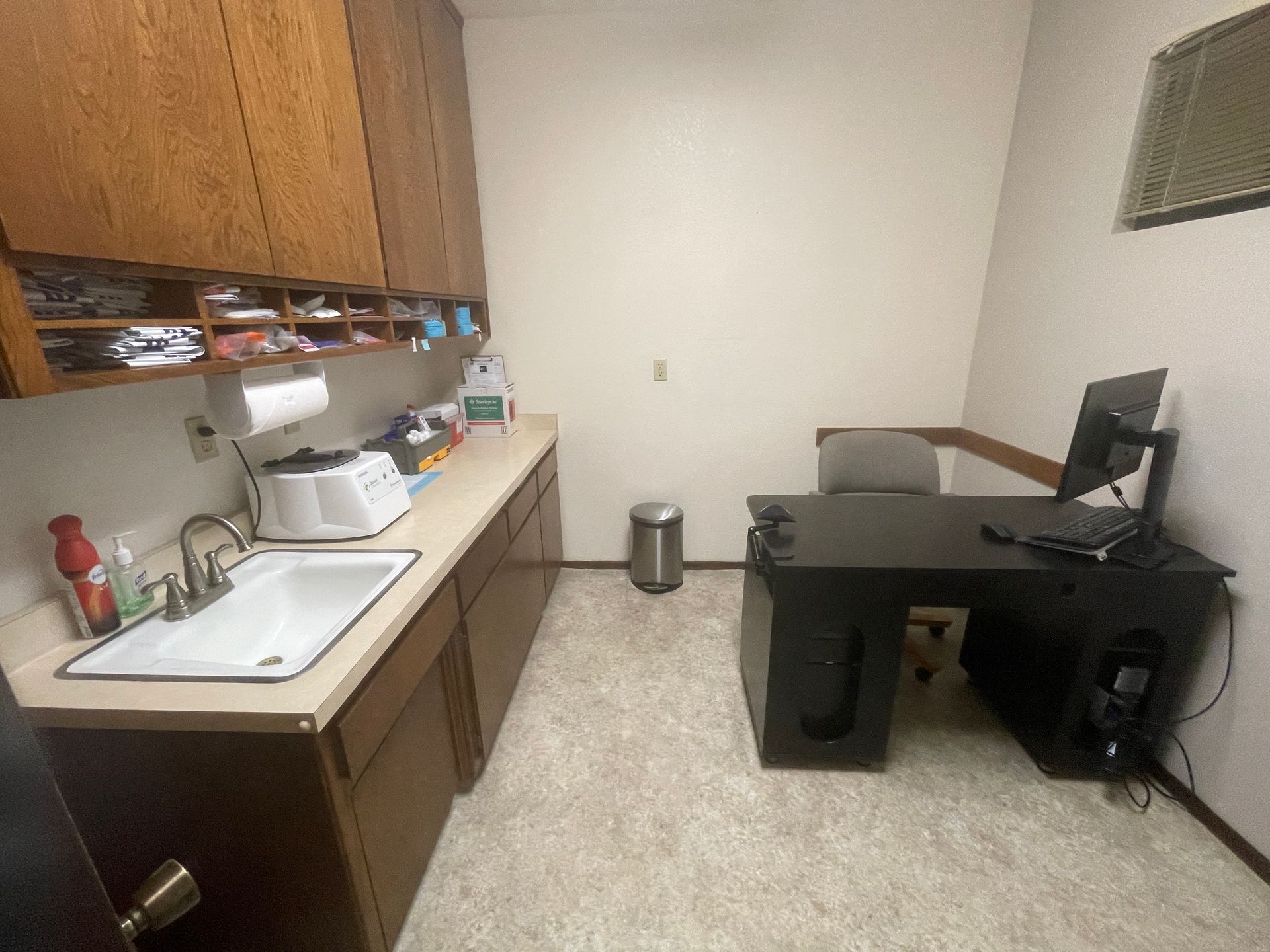 A kitchen with a sink , desk and computer.