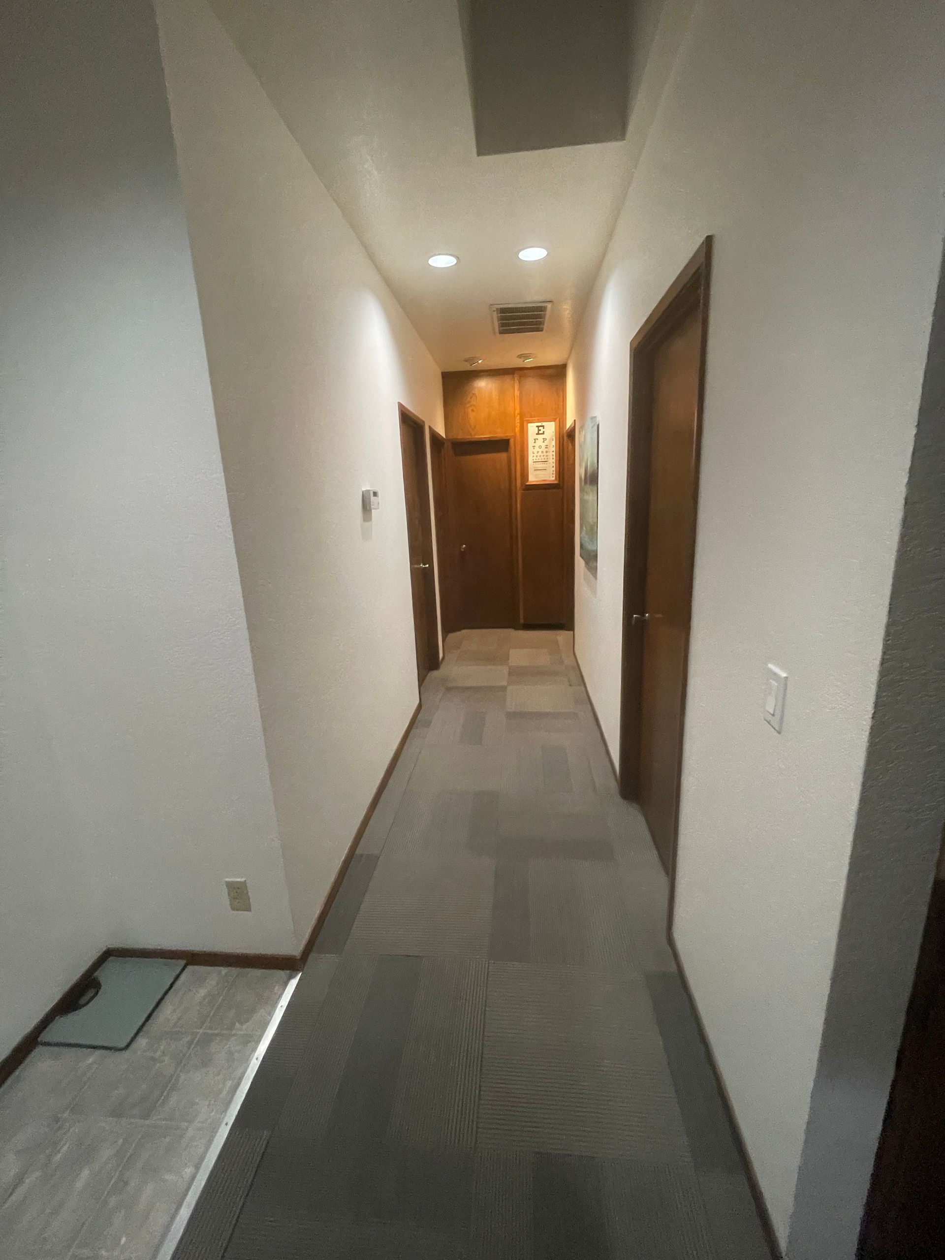 A long hallway with white walls and wooden doors
