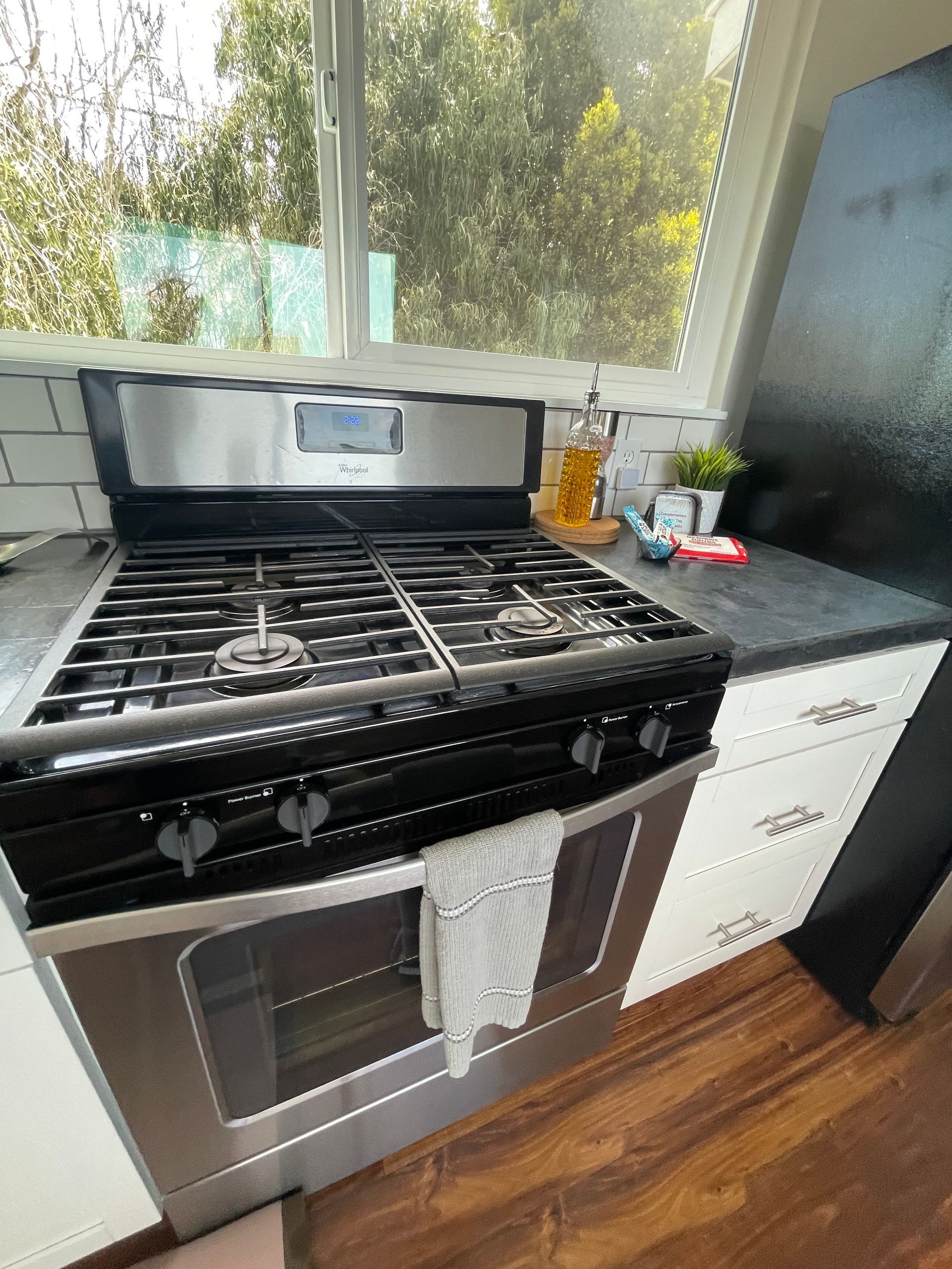 A stove with a towel on it is in a kitchen next to a window.