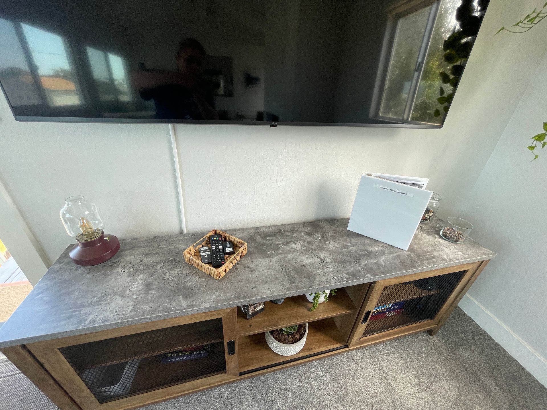 A television is mounted to the wall above a wooden entertainment center.