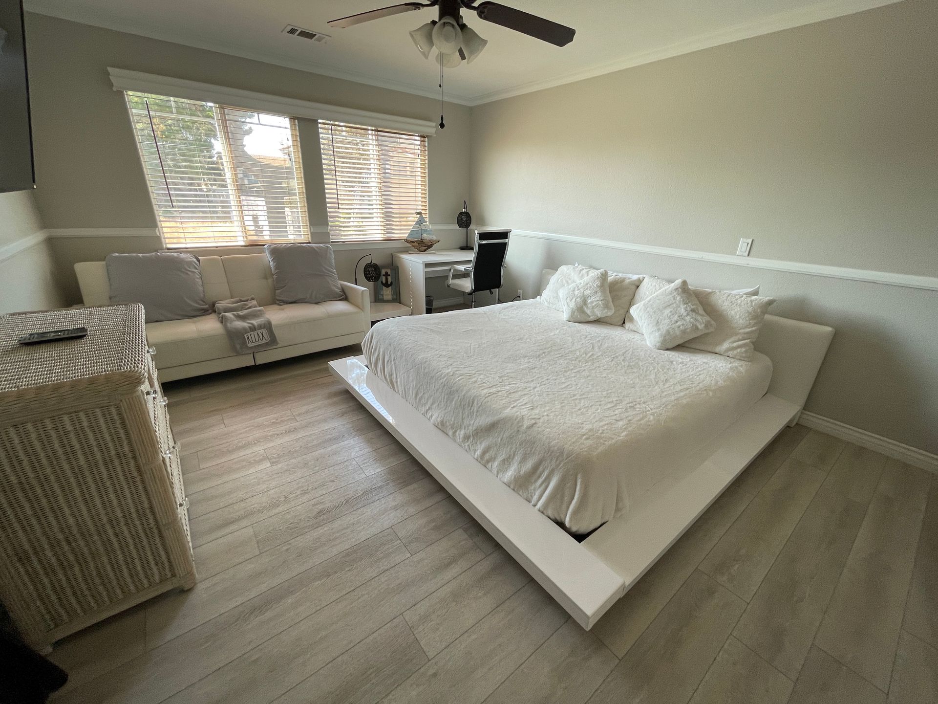 A bedroom with a bed , couch , desk and ceiling fan