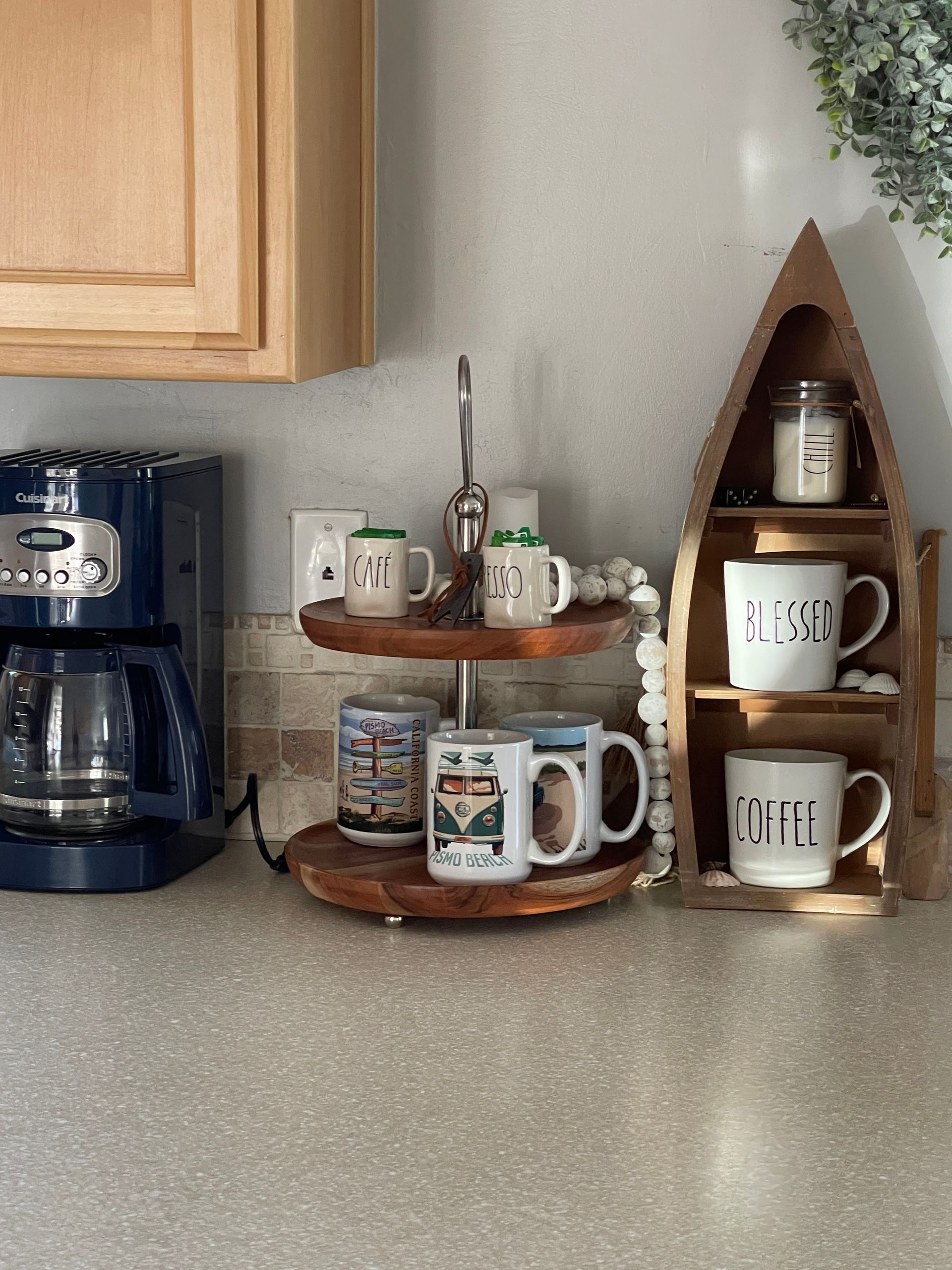A kitchen counter with a coffee maker and a wooden shelf with coffee mugs on it.