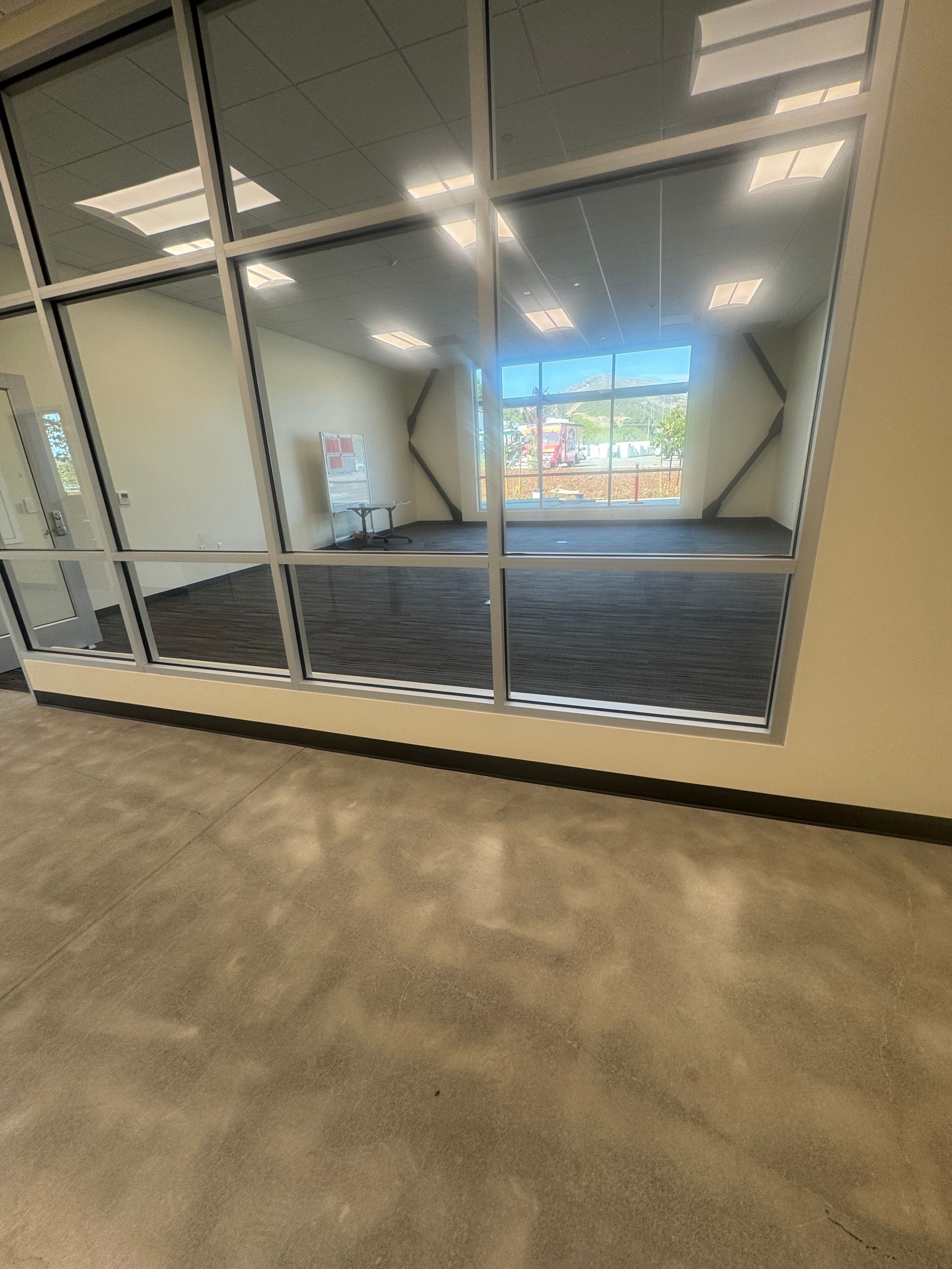 Interior of a room with large windows, a gray floor, and dark gray carpet.