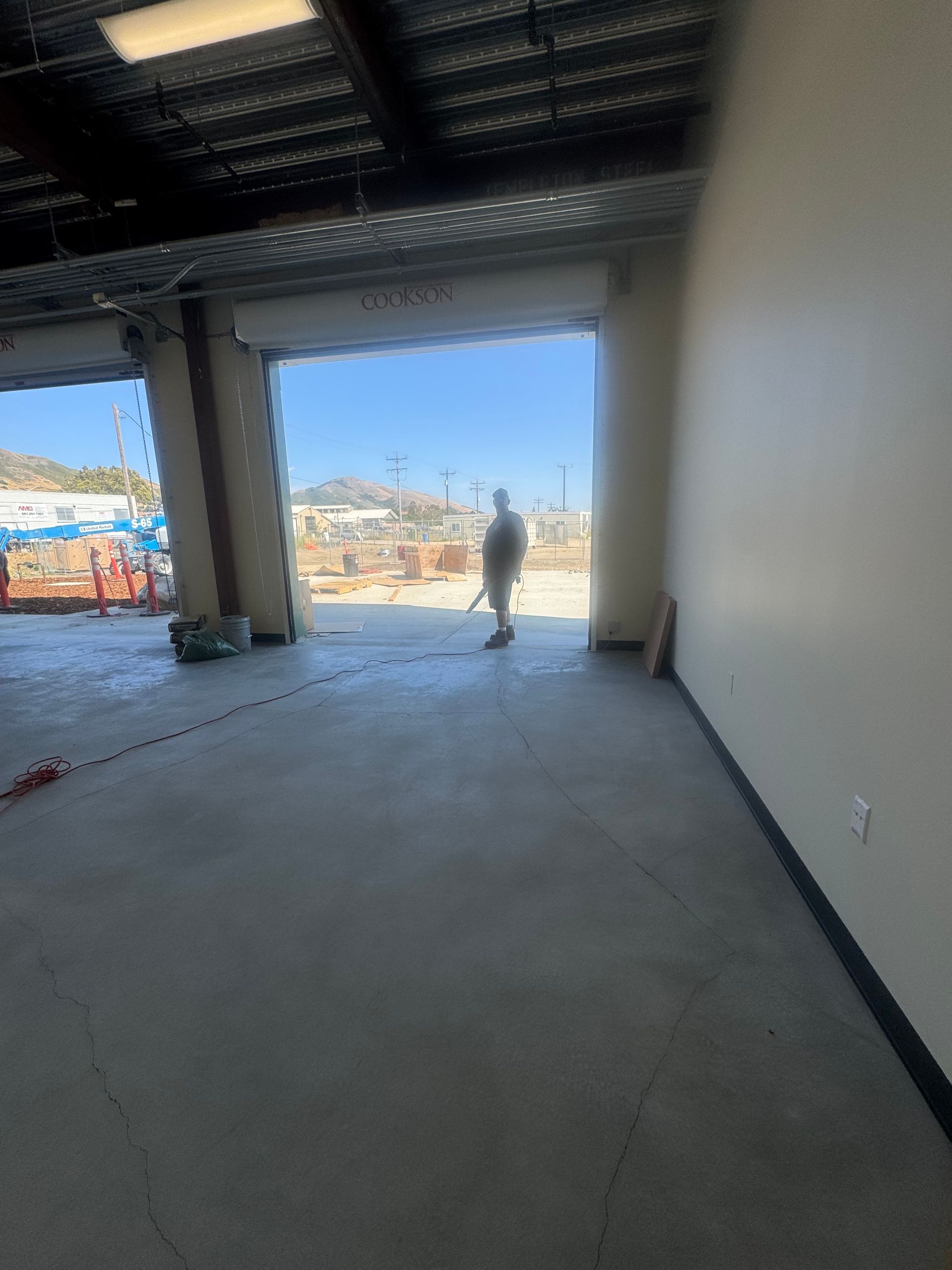 Inside view of an empty warehouse with open garage door. A person stands outside.