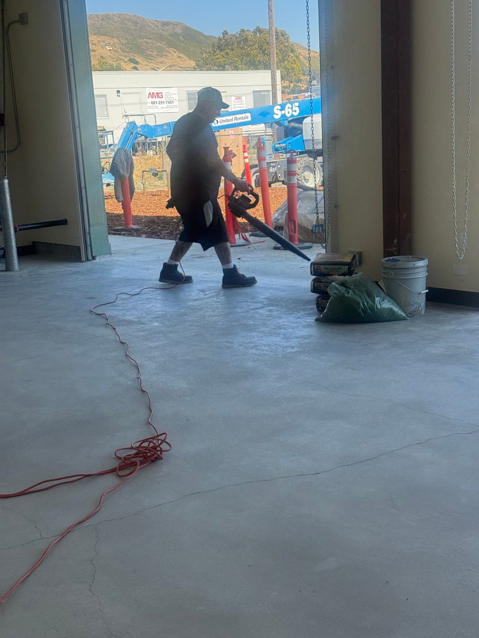 A man using a leaf blower inside a building, blowing debris.
