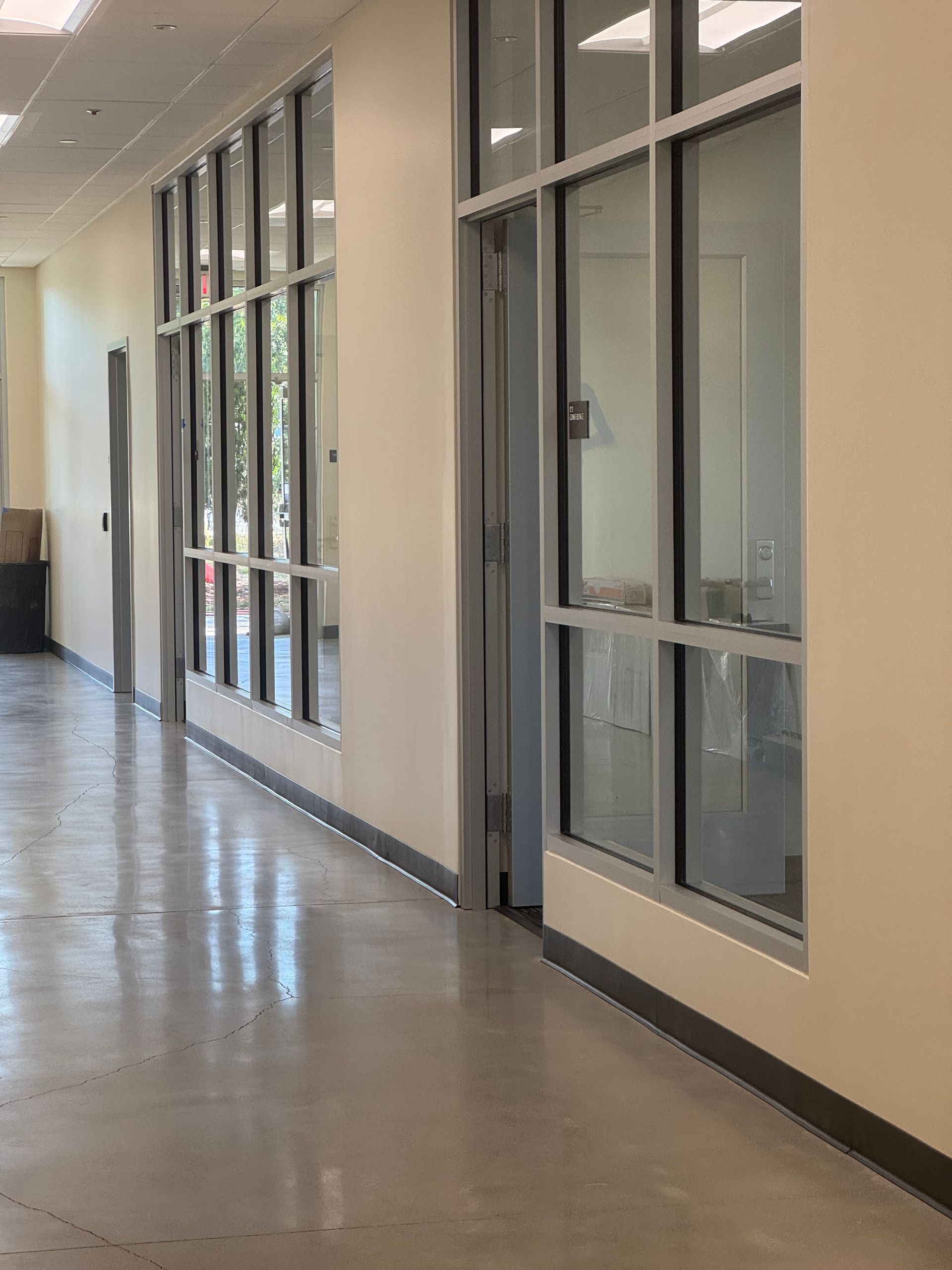 Hallway with tall windows and a concrete floor.