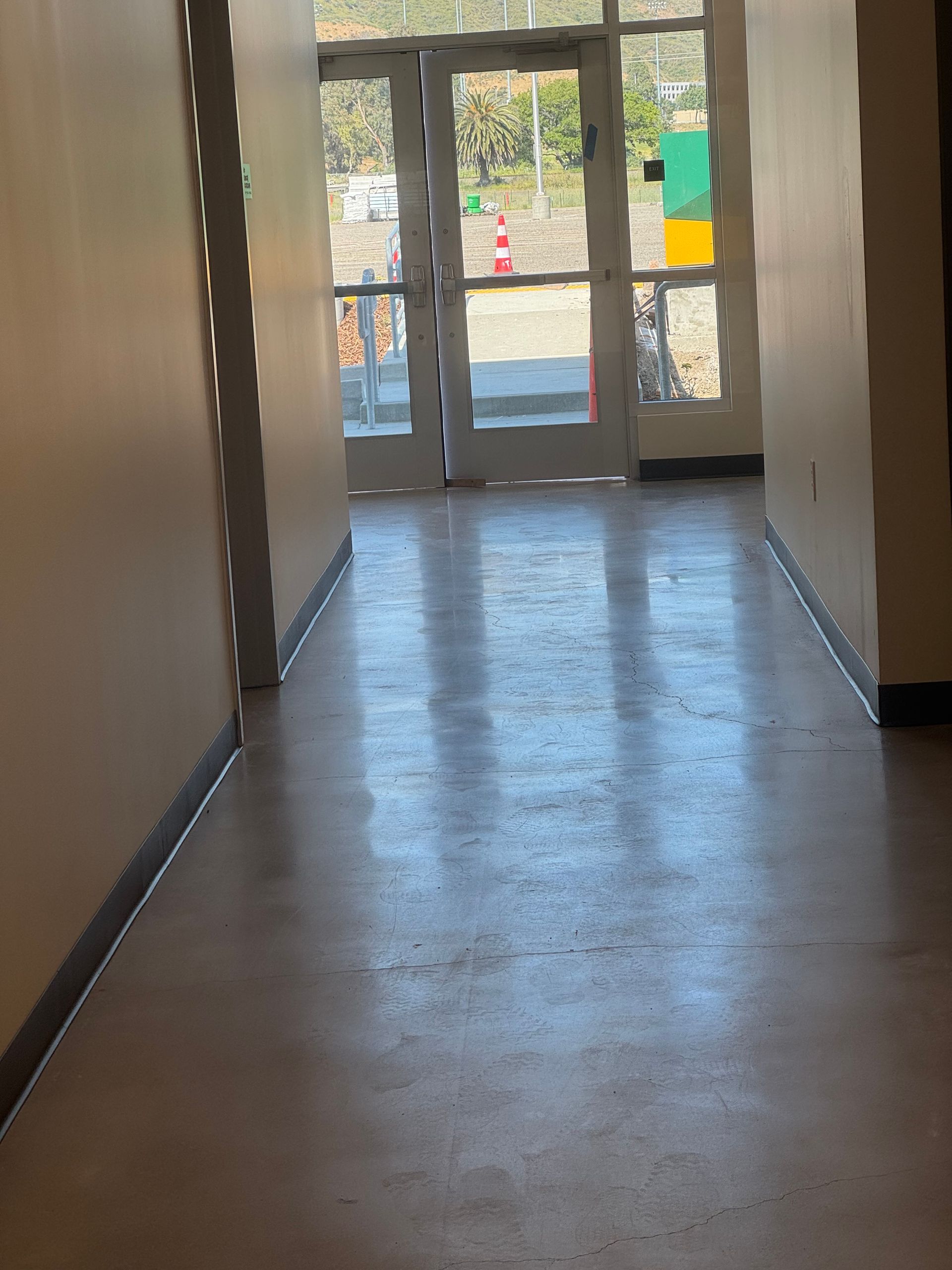 Hallway with doors at the end, light brown walls and floor.