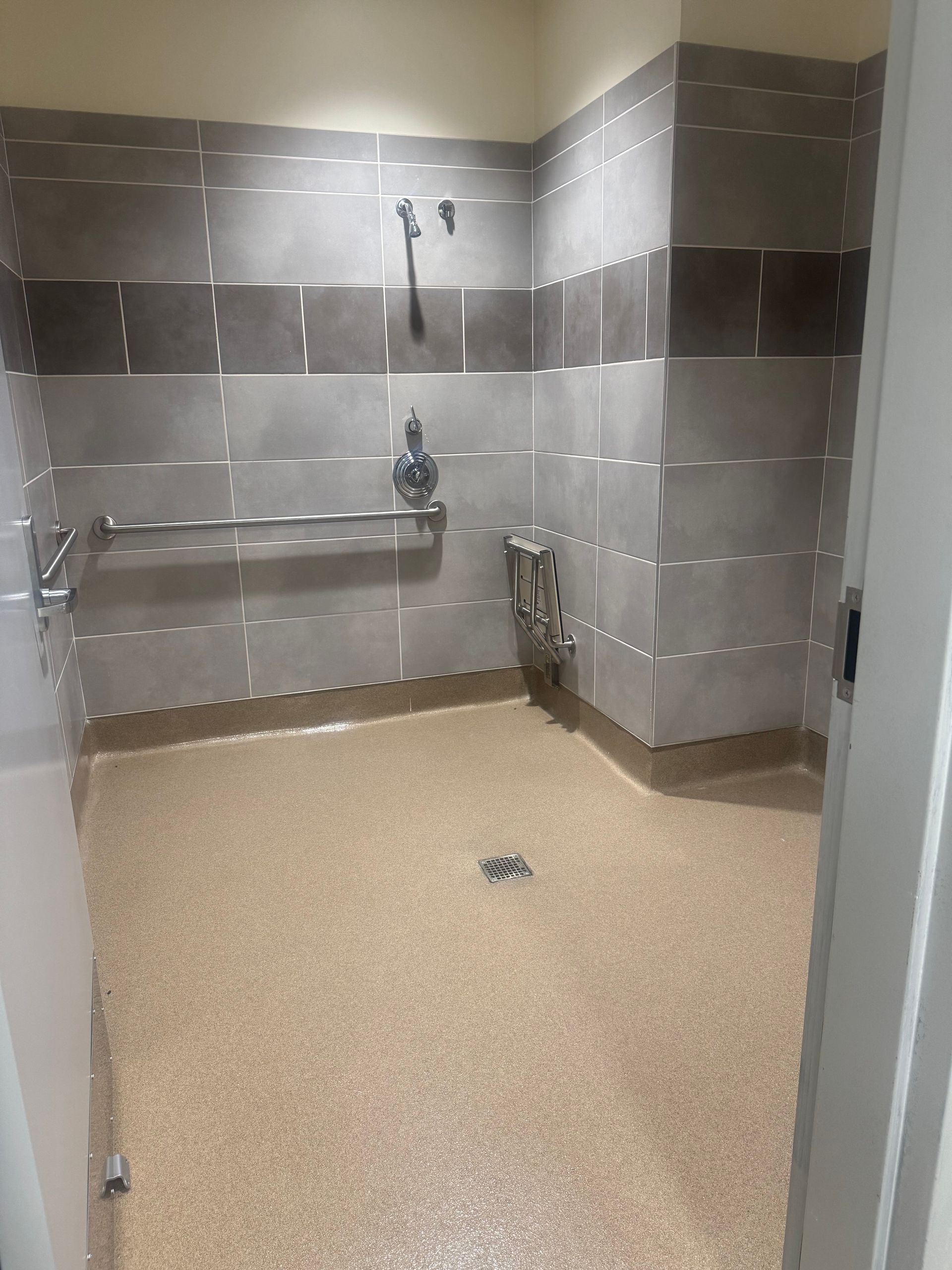 Accessible shower with grab bars, built-in seat, and a neutral color scheme.