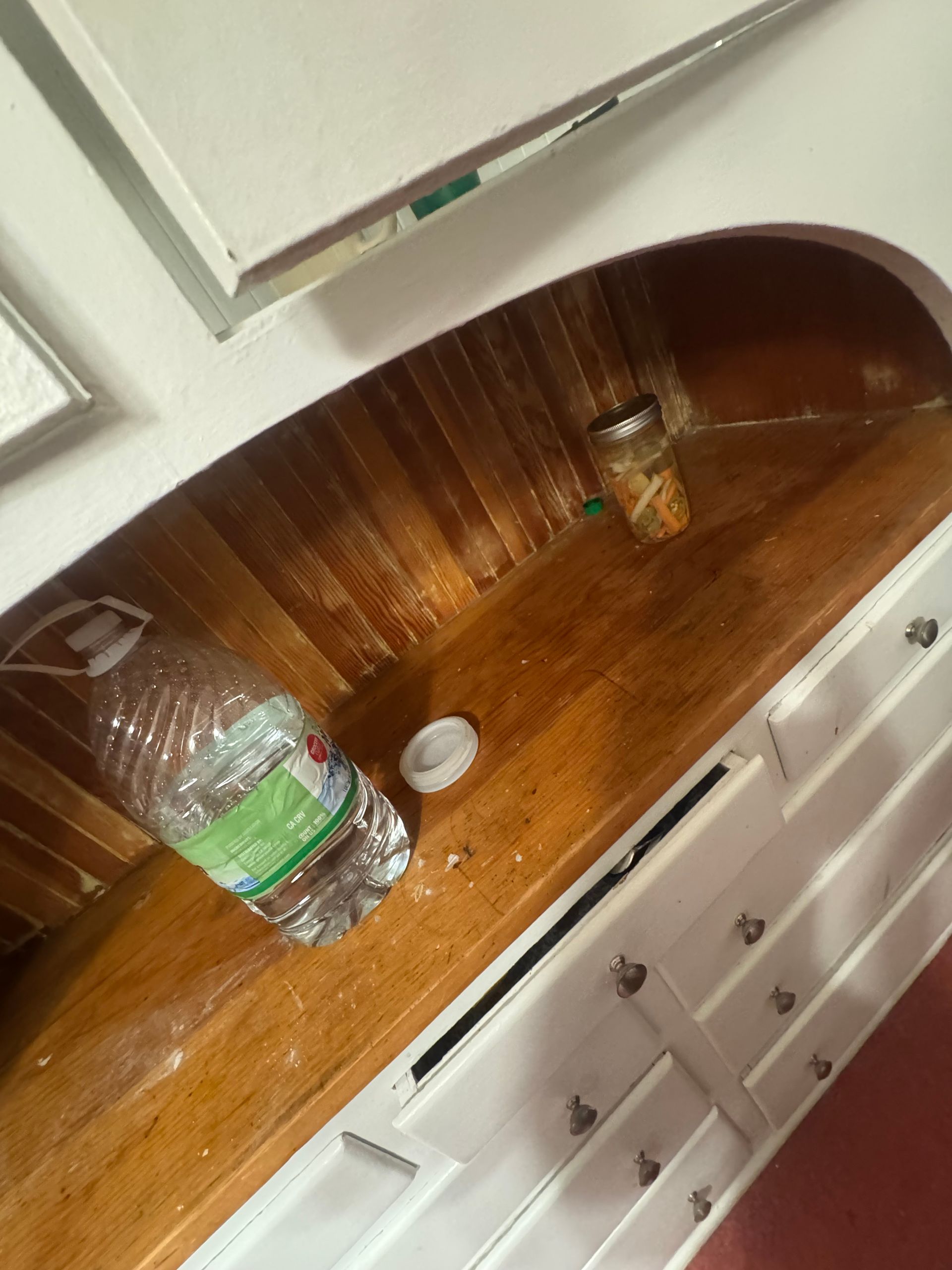 Wooden boat interior with water bottle, jar, and white trim.