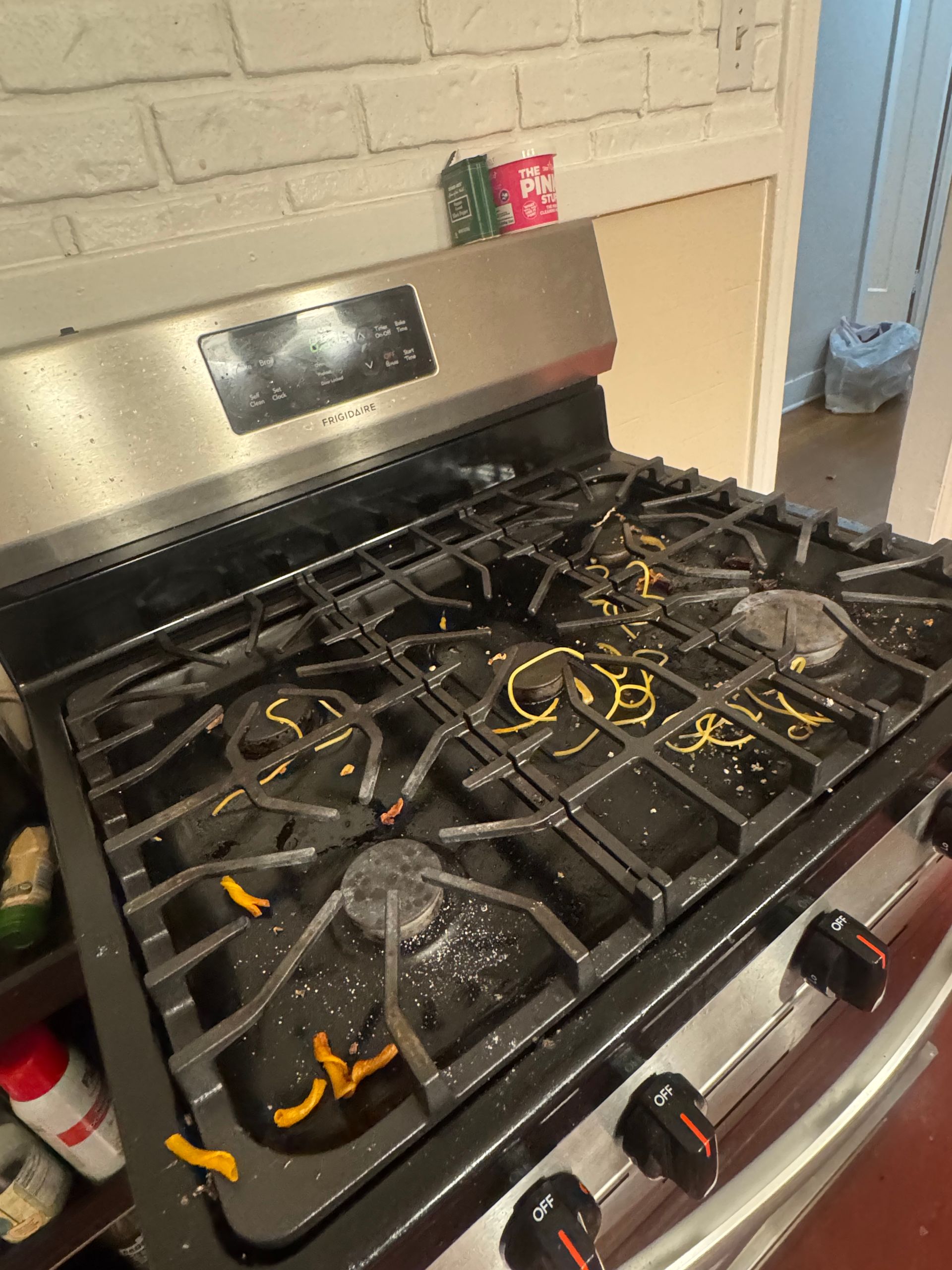A dirty stovetop covered in food debris, in a kitchen.