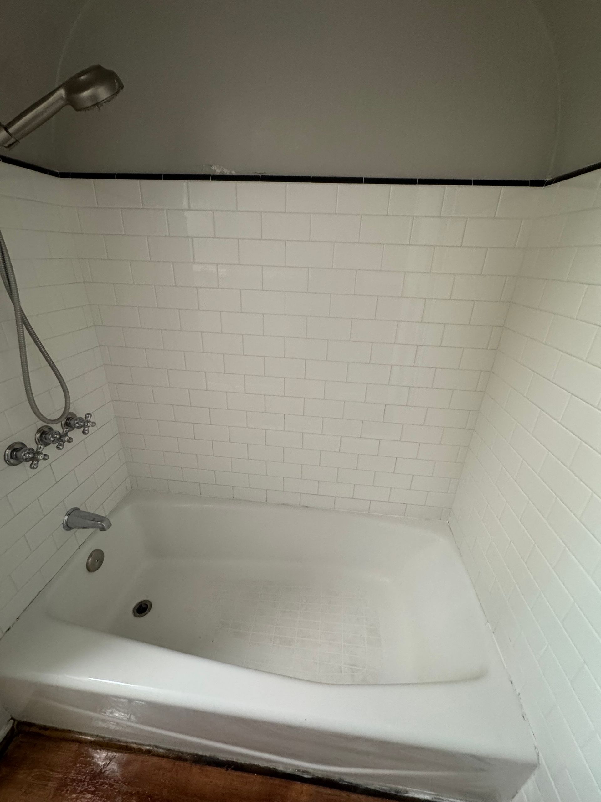 White tiled shower with a bathtub and showerhead.