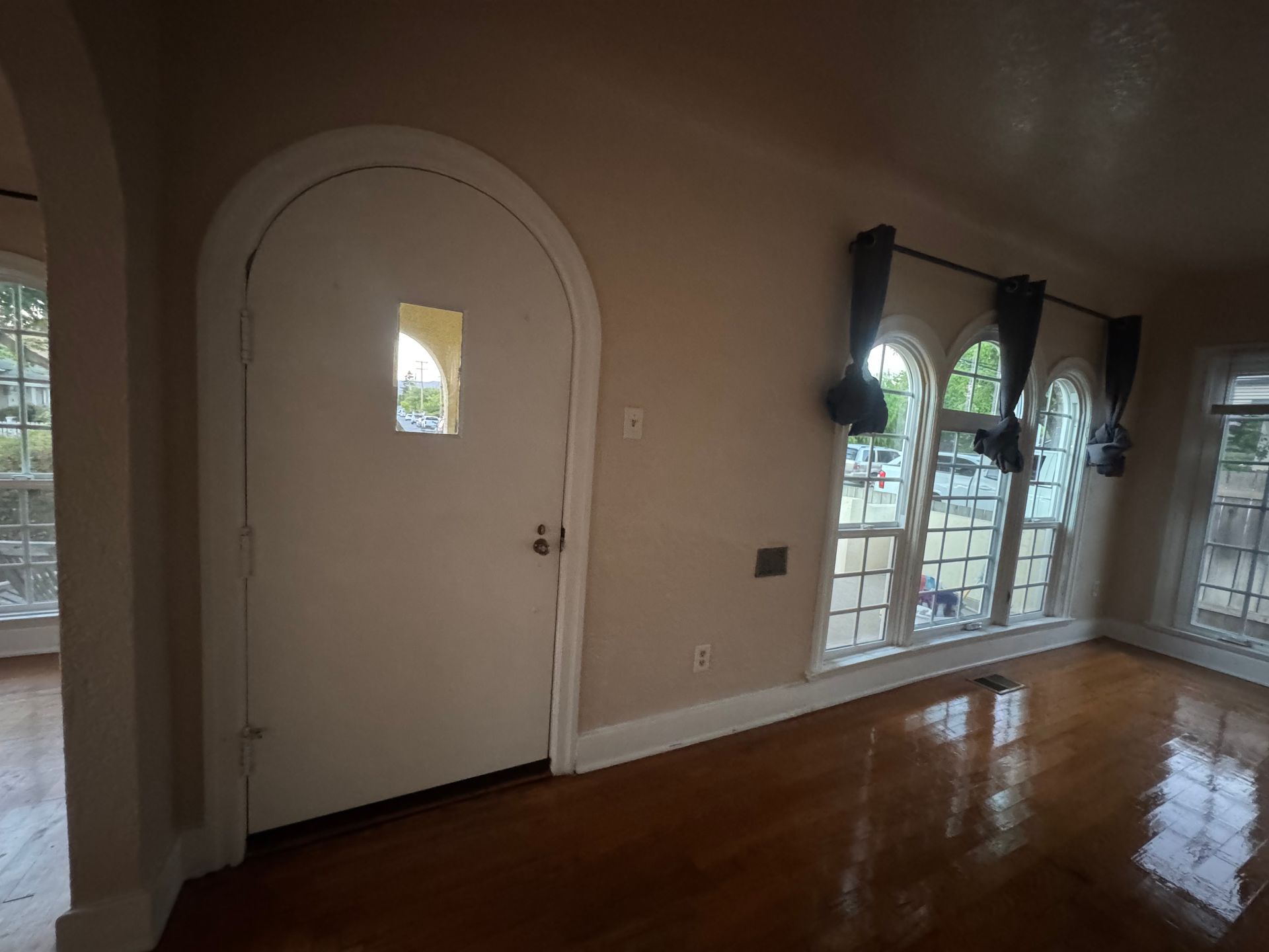 Interior room with arched door, ornate windows, and hardwood floors.
