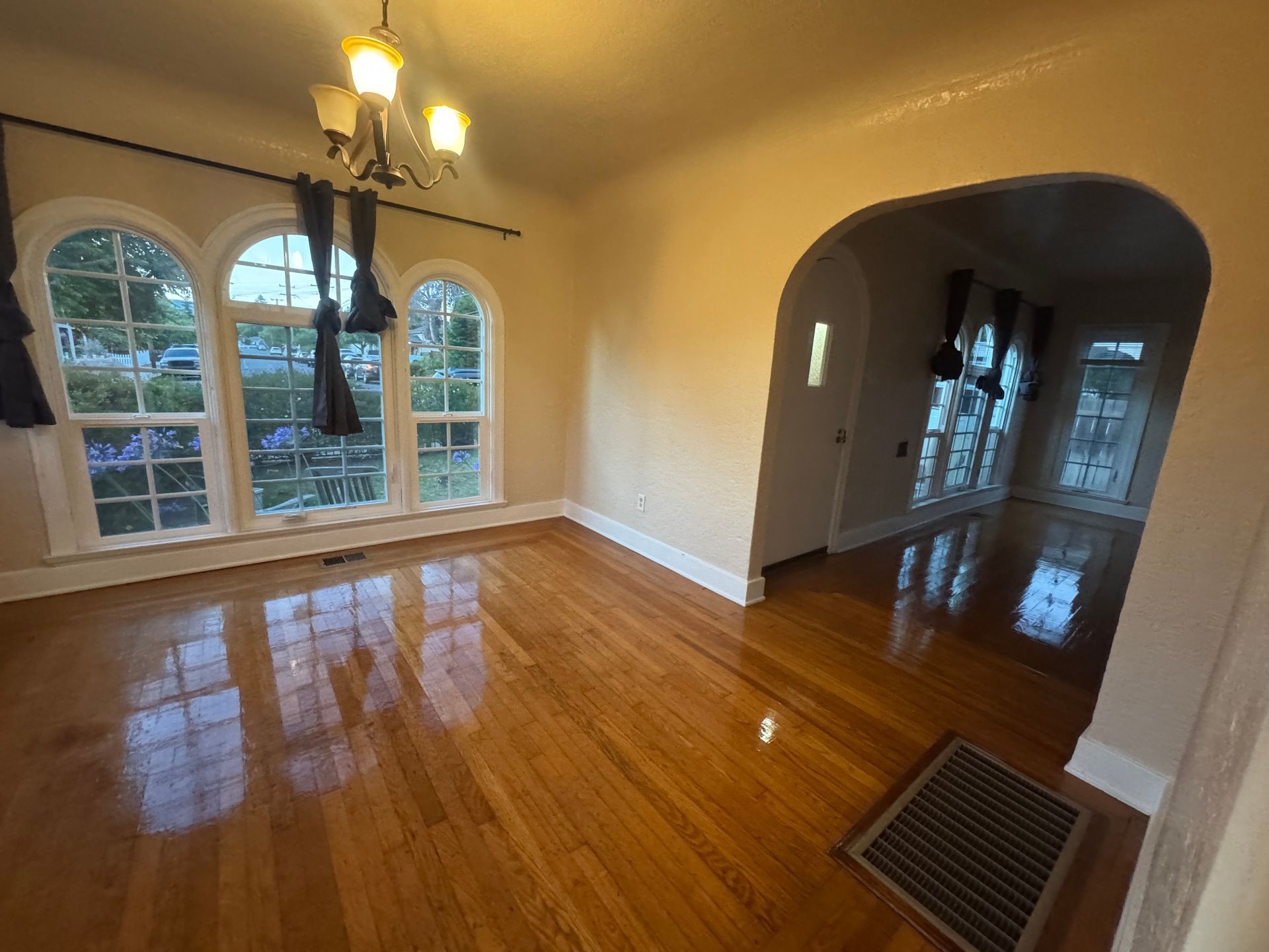 Dining room with arched windows, hardwood floors, and an archway leading to a hallway.