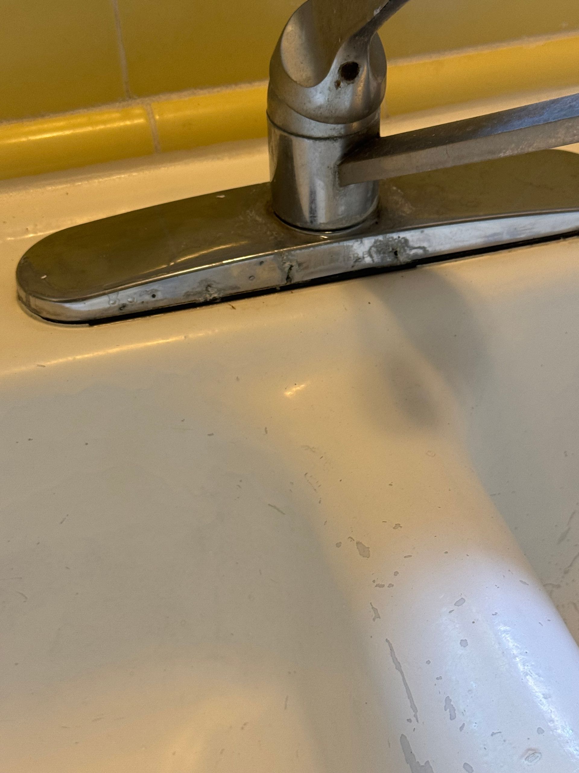 A close-up of a white kitchen sink with a silver faucet.
