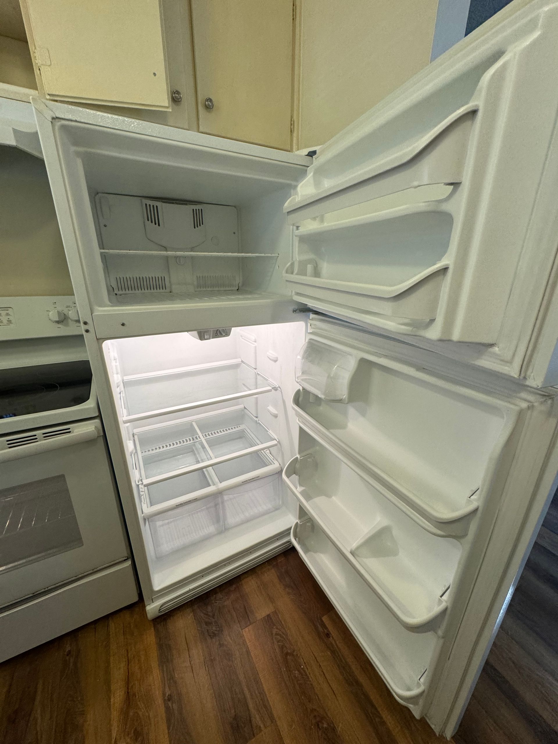 White refrigerator with open doors, showing the inside shelves and compartments.