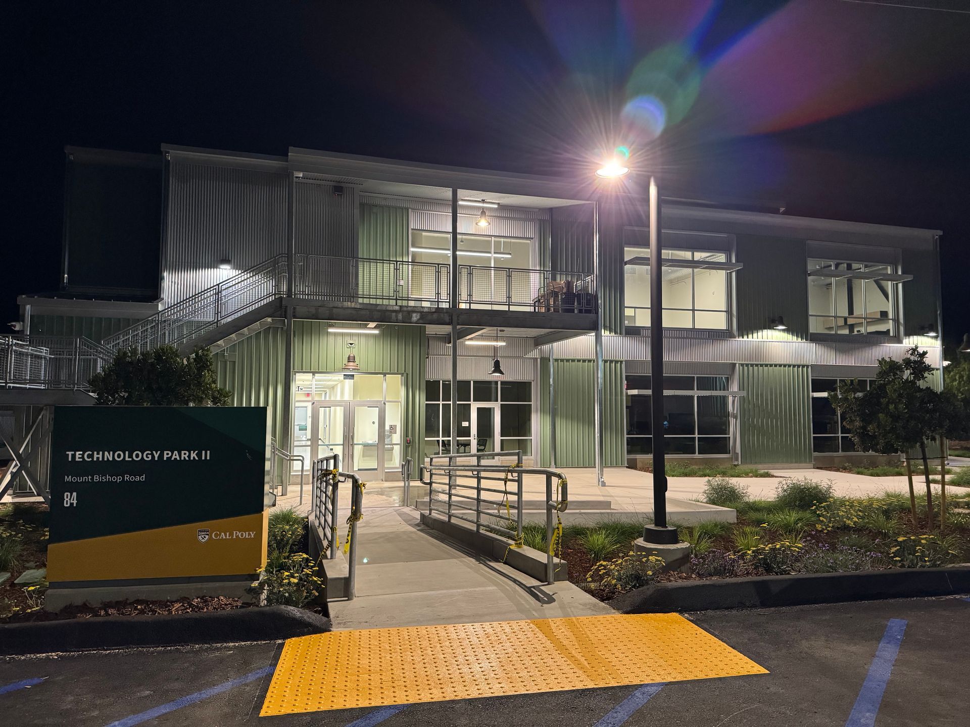 Nighttime view of Tech-House building with lighted sign, entrance, and ramp.