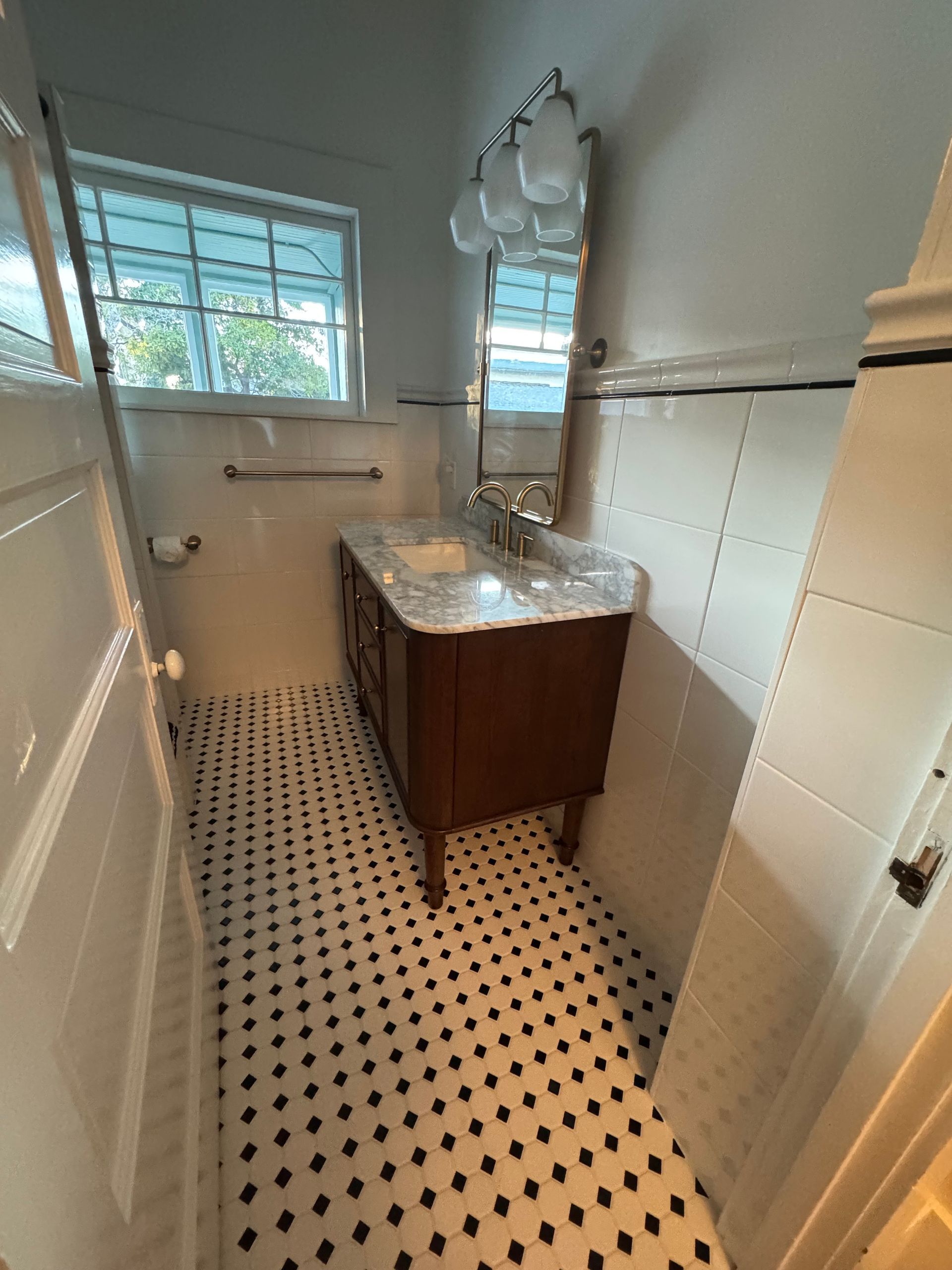 Bathroom with dark wood vanity, patterned tile floor, and small window.