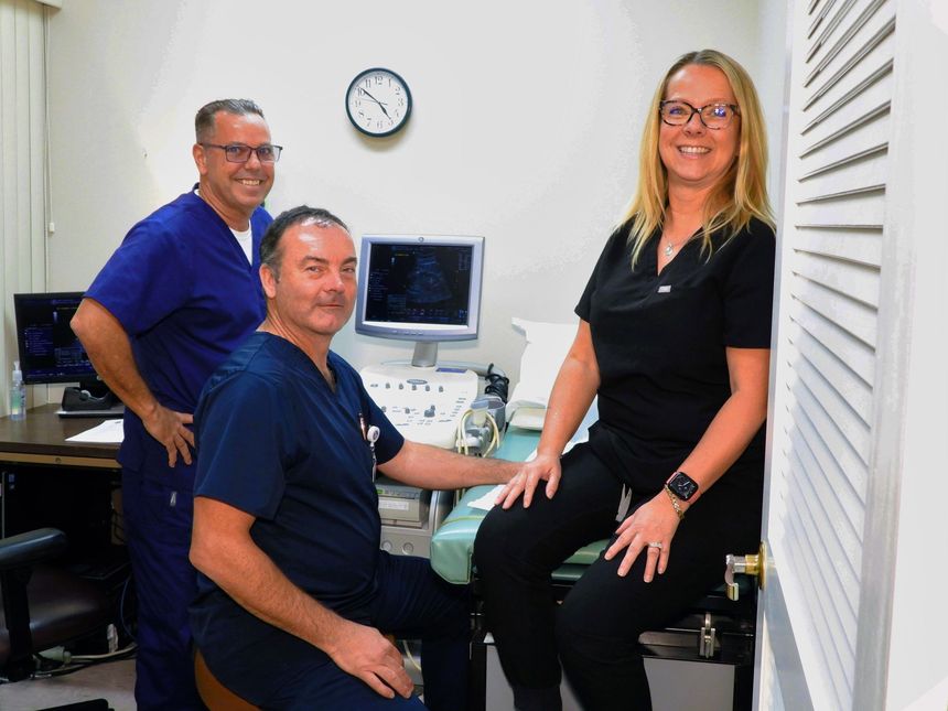 A group of doctors are posing for a picture in a hospital room.