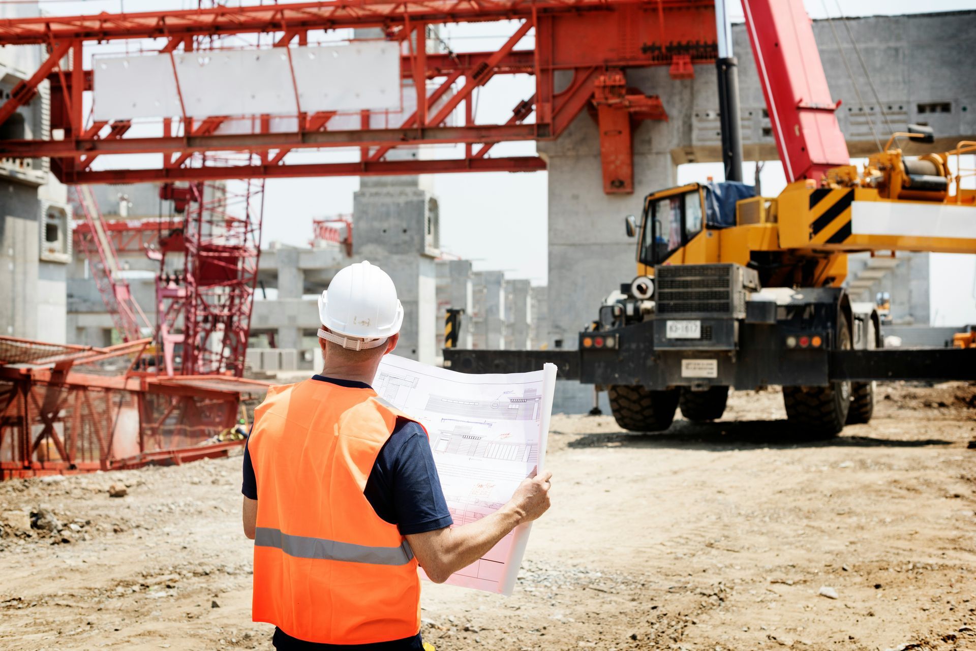 Construction worker in orange vest and white hard hat.