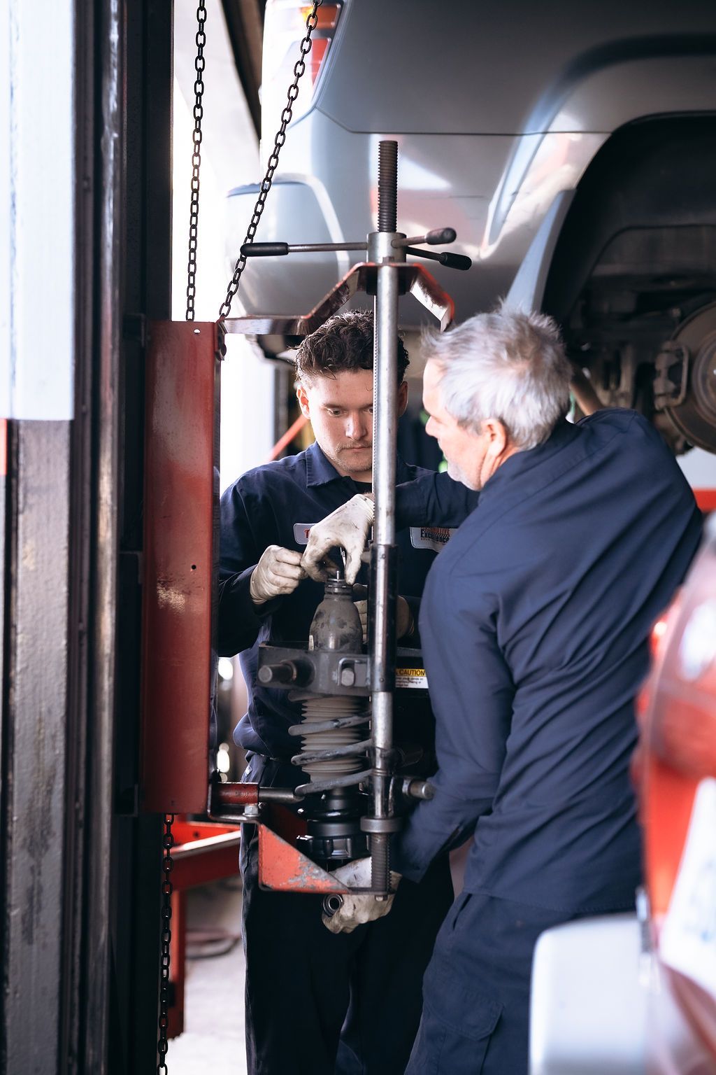 Two men are working on a car in a garage.