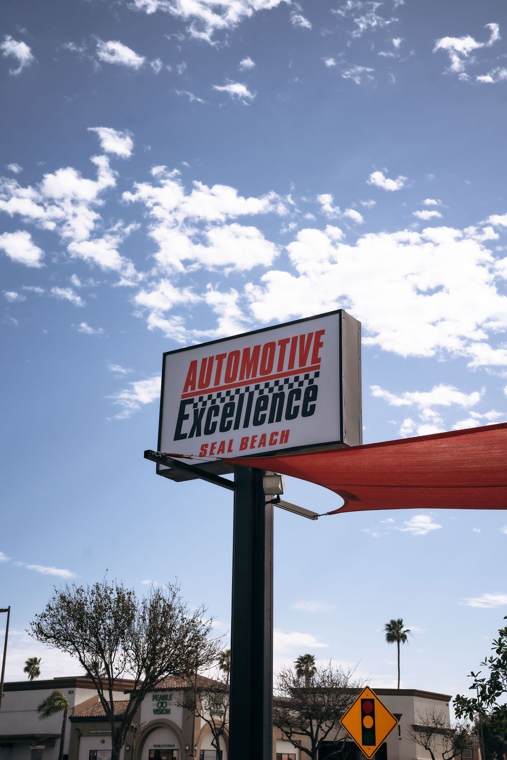 A sign for automotive excellence is hanging from a pole.