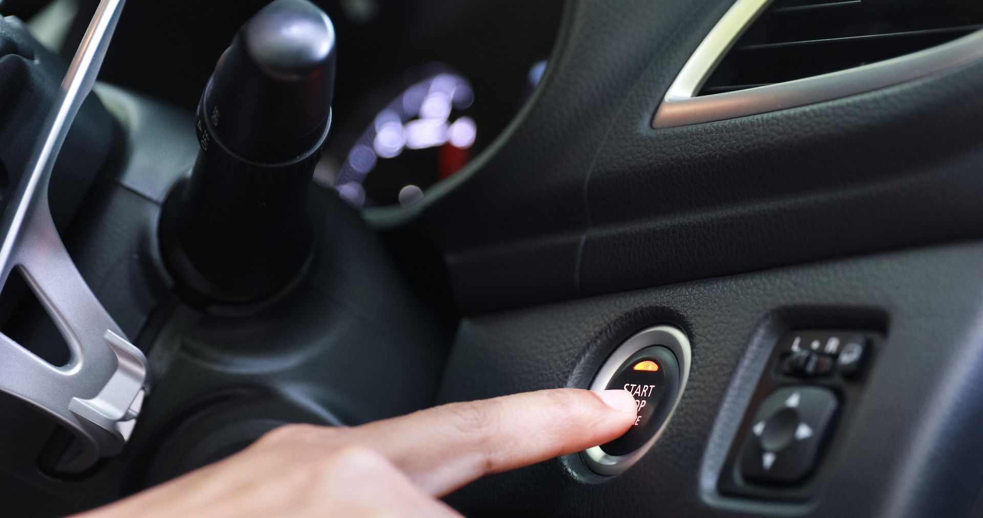 A person is pressing a button on the dashboard of a car.