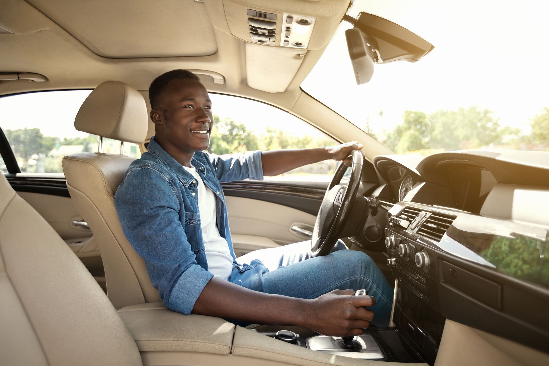 A man is driving a car on a sunny day.