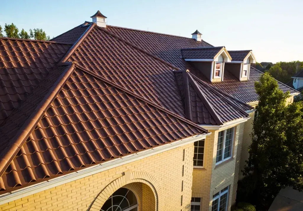 Aerial view of a house with a red tile roof and two dormer windows in sunlight