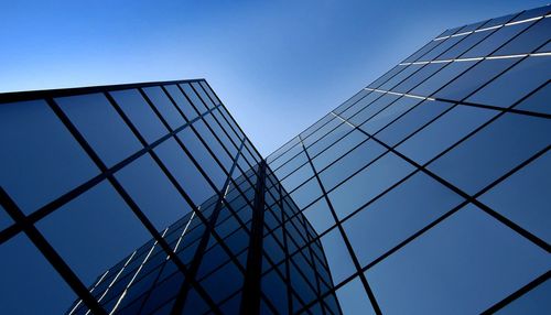 Reflective glass skyscrapers viewed from below against a blue sky