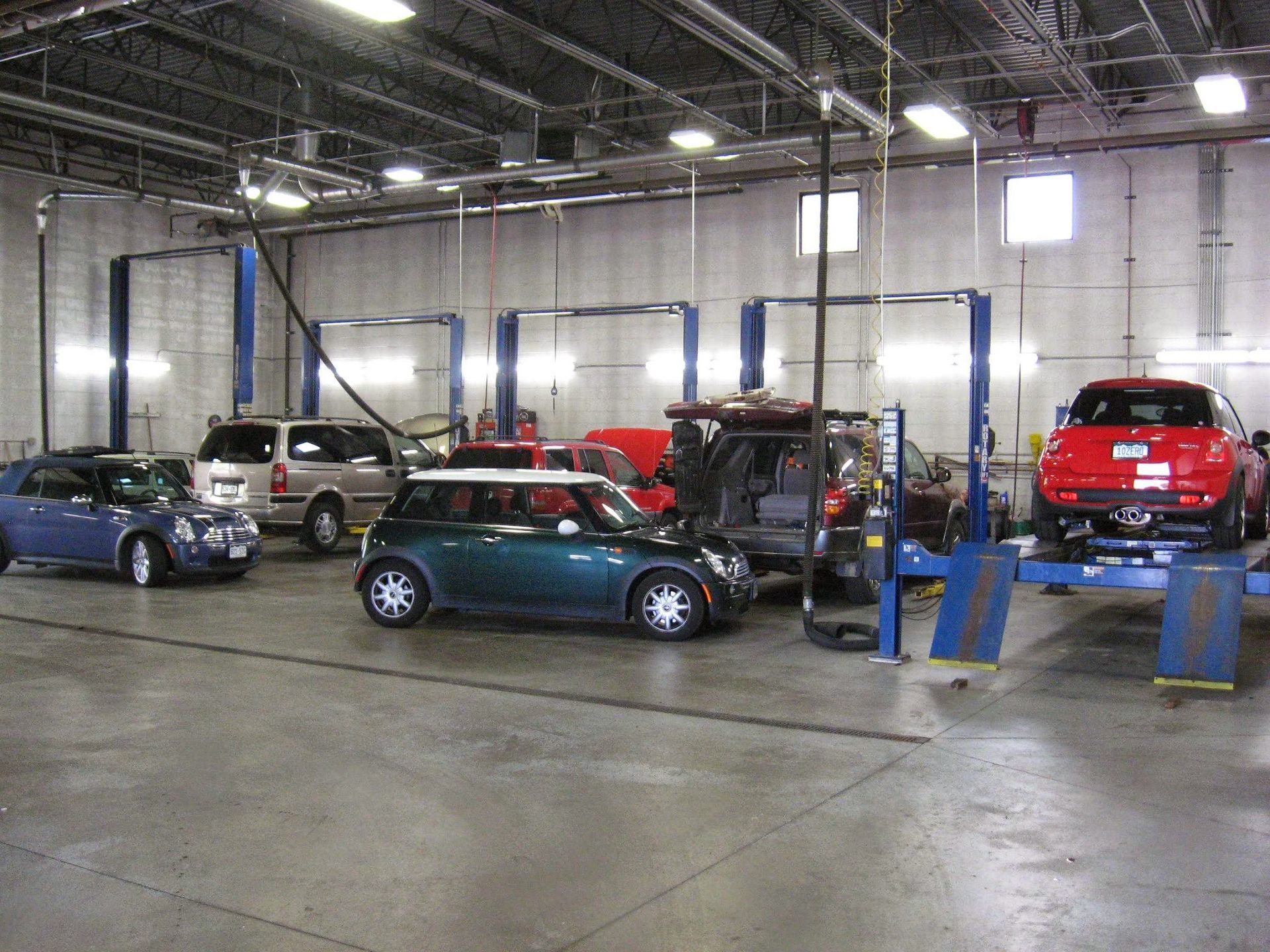 Auto repair shop with cars on lifts, a Mini Cooper, and a red car. | 5th Gear Automotive