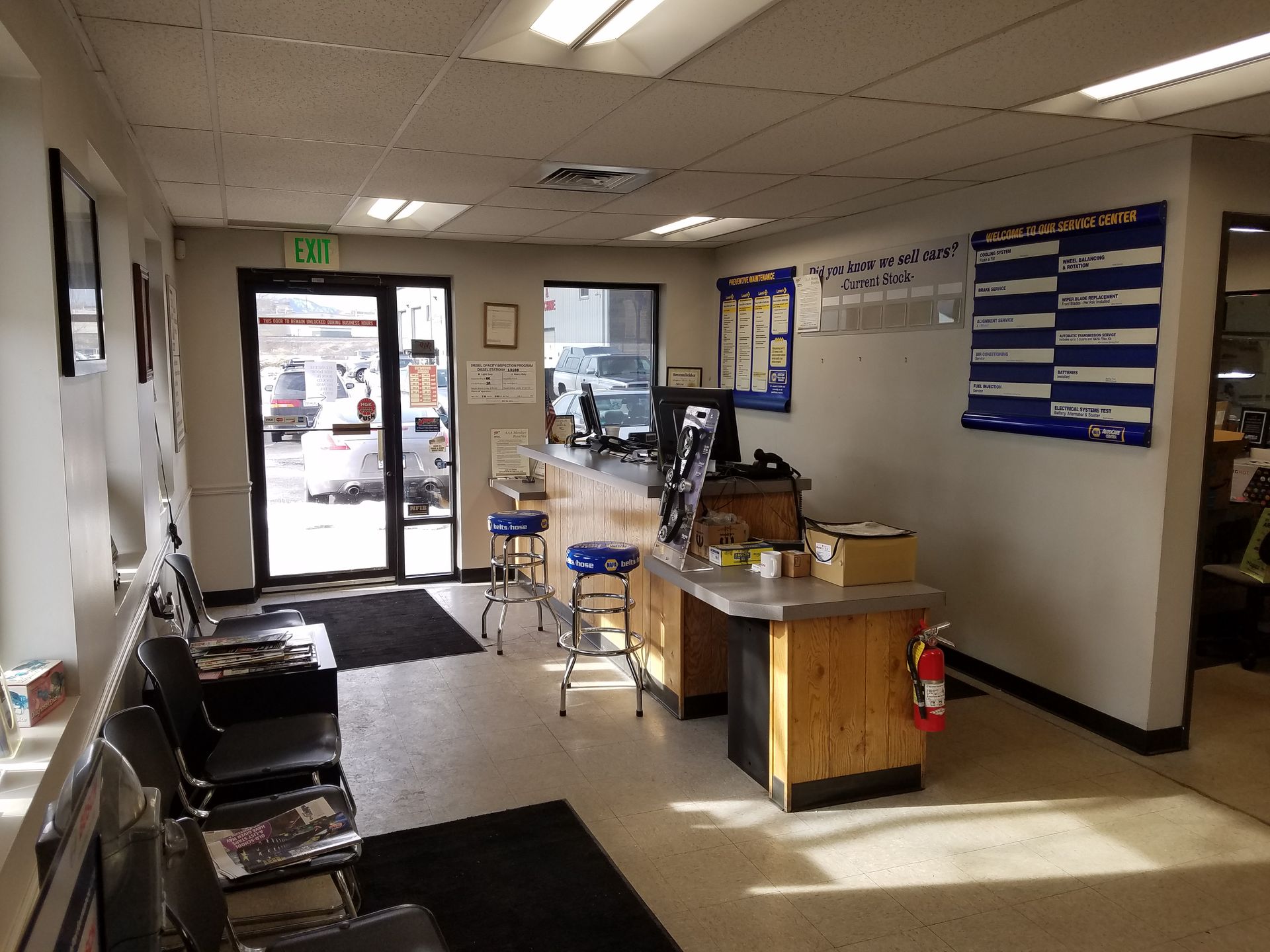 Interior of a car repair shop. Waiting area with chairs, counter, and door to outside with vehicles. | 5th Gear Automotive