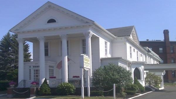 White building with columns, likely a funeral home, sunny day.