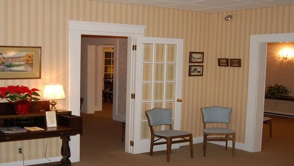 Interior with chairs, doors, and a table in a room with light peach striped wallpaper.