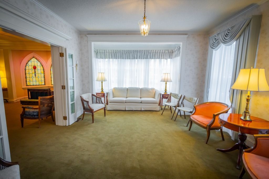 Funeral home waiting room with a couch, chairs, and lamps.