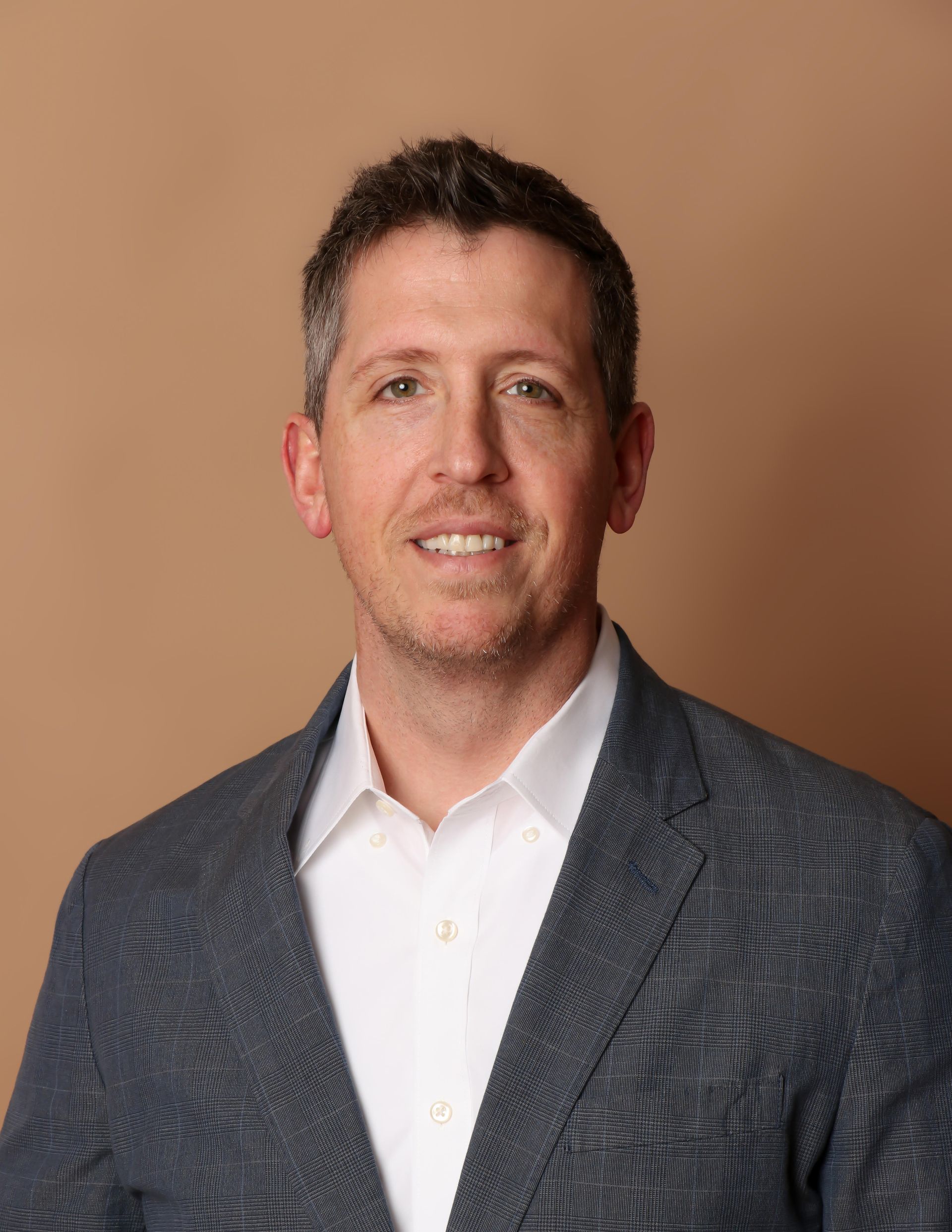 A man with a beard is wearing a suit and smiling